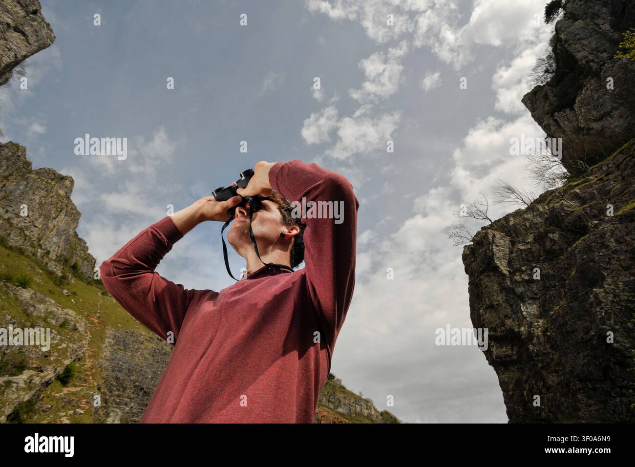 young man looking at mountain view through binoculars Stock Photo