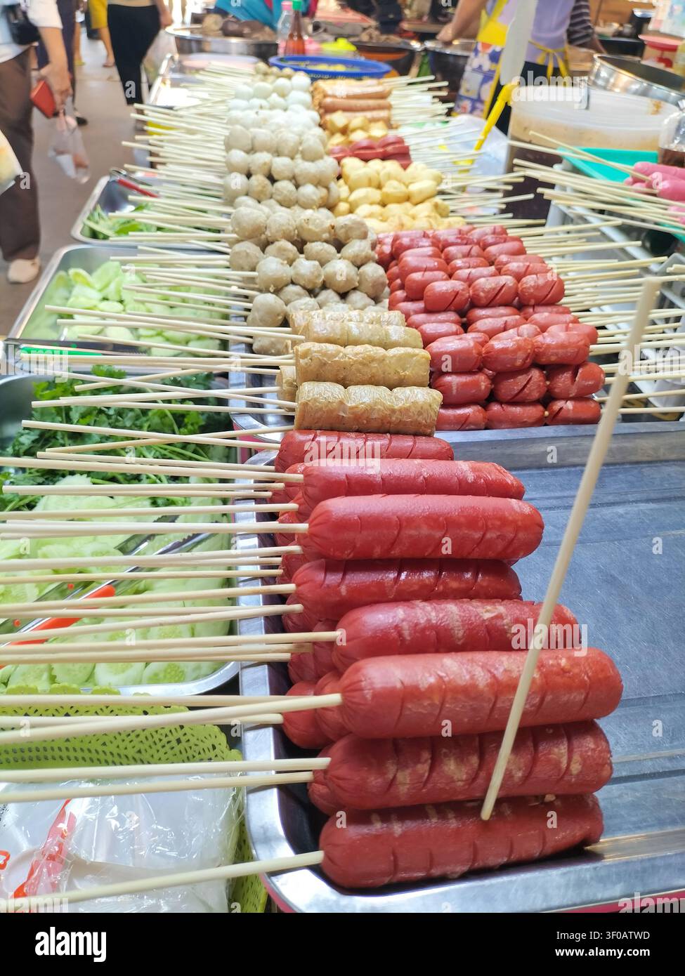 Assorted meatballs and sausages on wooden skewers neatly displayed at a local Thai street food stall. - Smartphone Captured Stock Image