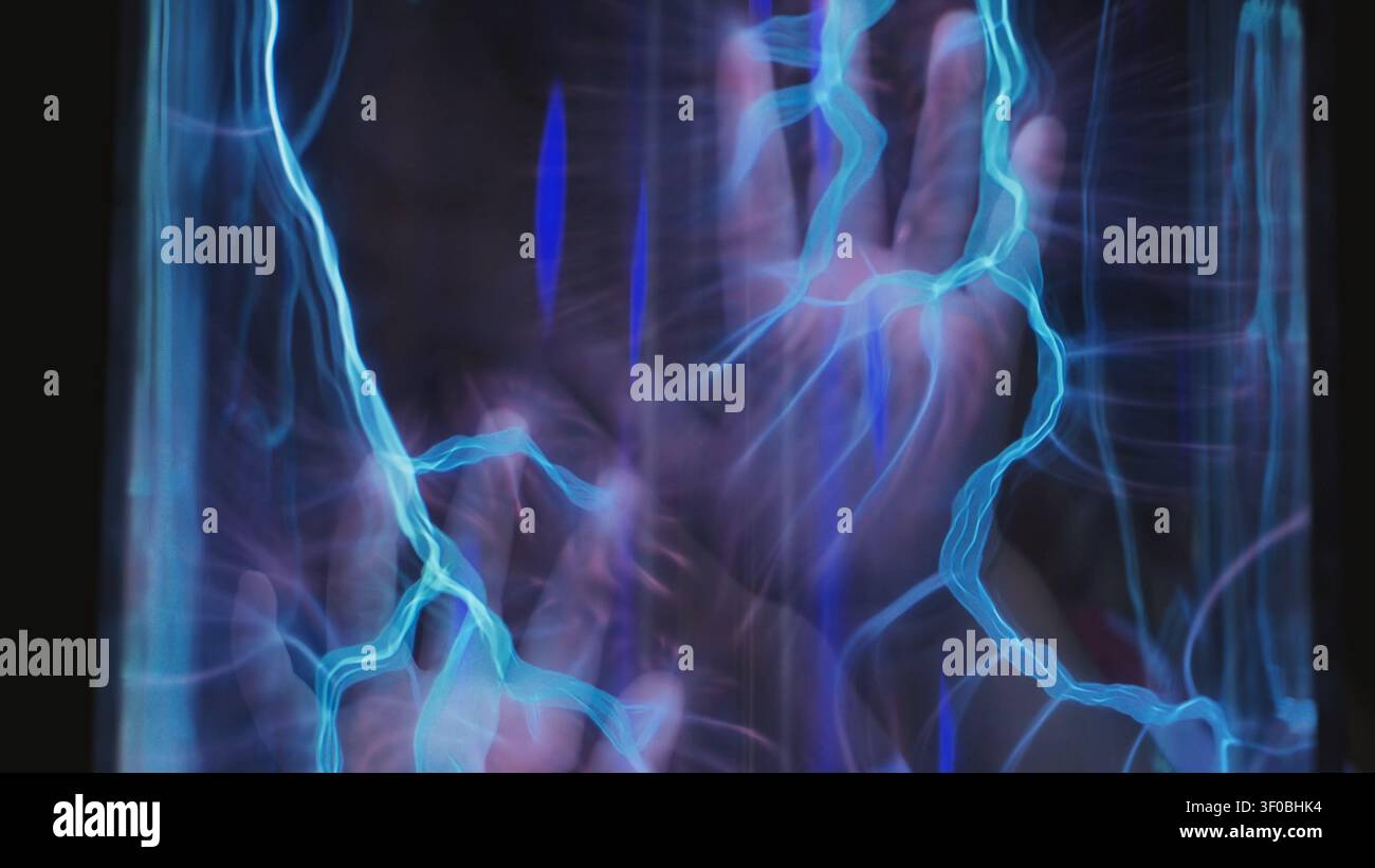 Hand touching plasma ball, creating blue electrical energy streams and static electricity Stock Photo