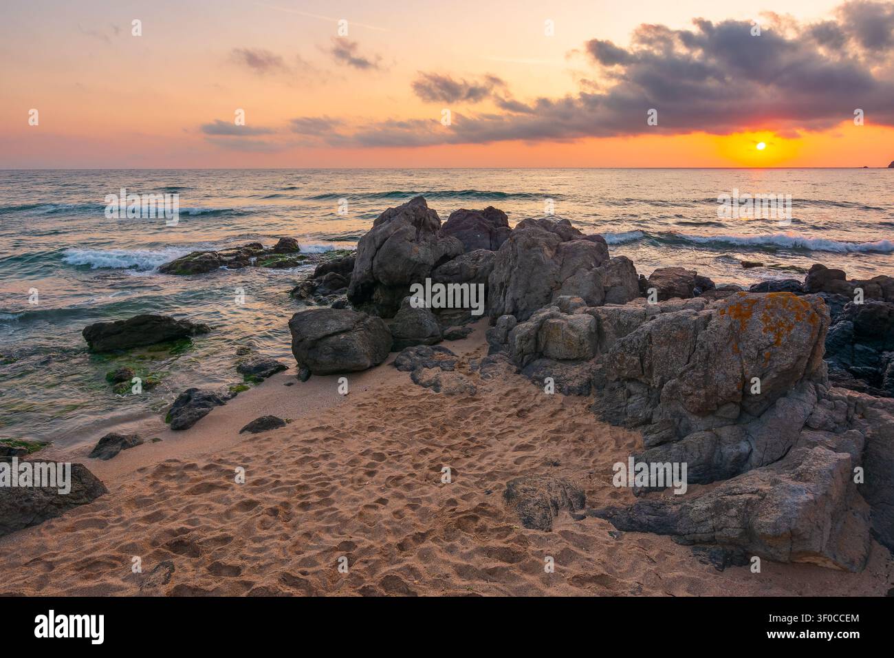 huge stones on a sandy beach at sunrise. wonderful summer vacation season at the black sea. calm waves washing the sand shore. nature background with Stock Photo