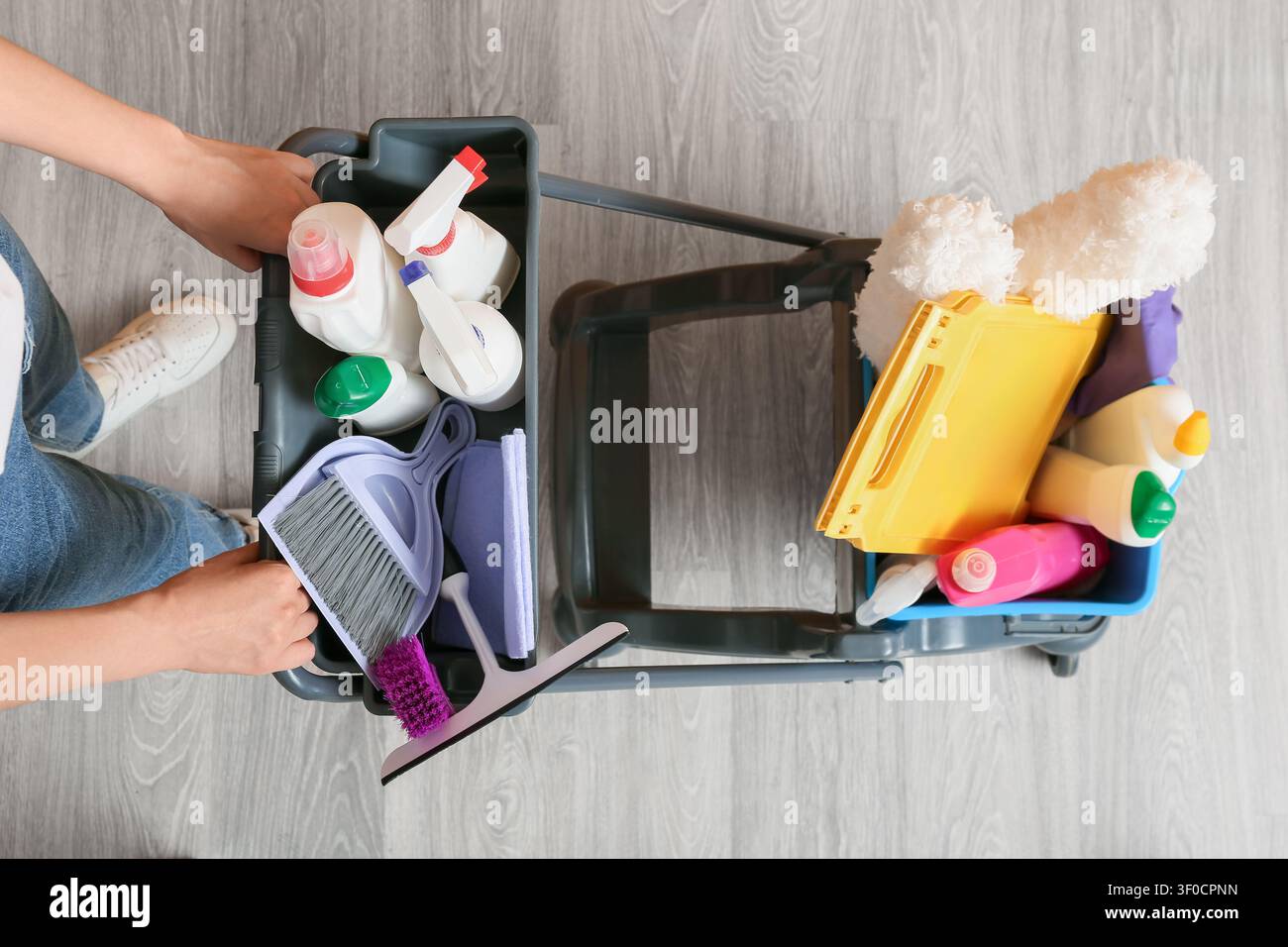 Person pushing cleaning supplies cart with various cleaning products Stock Photo
