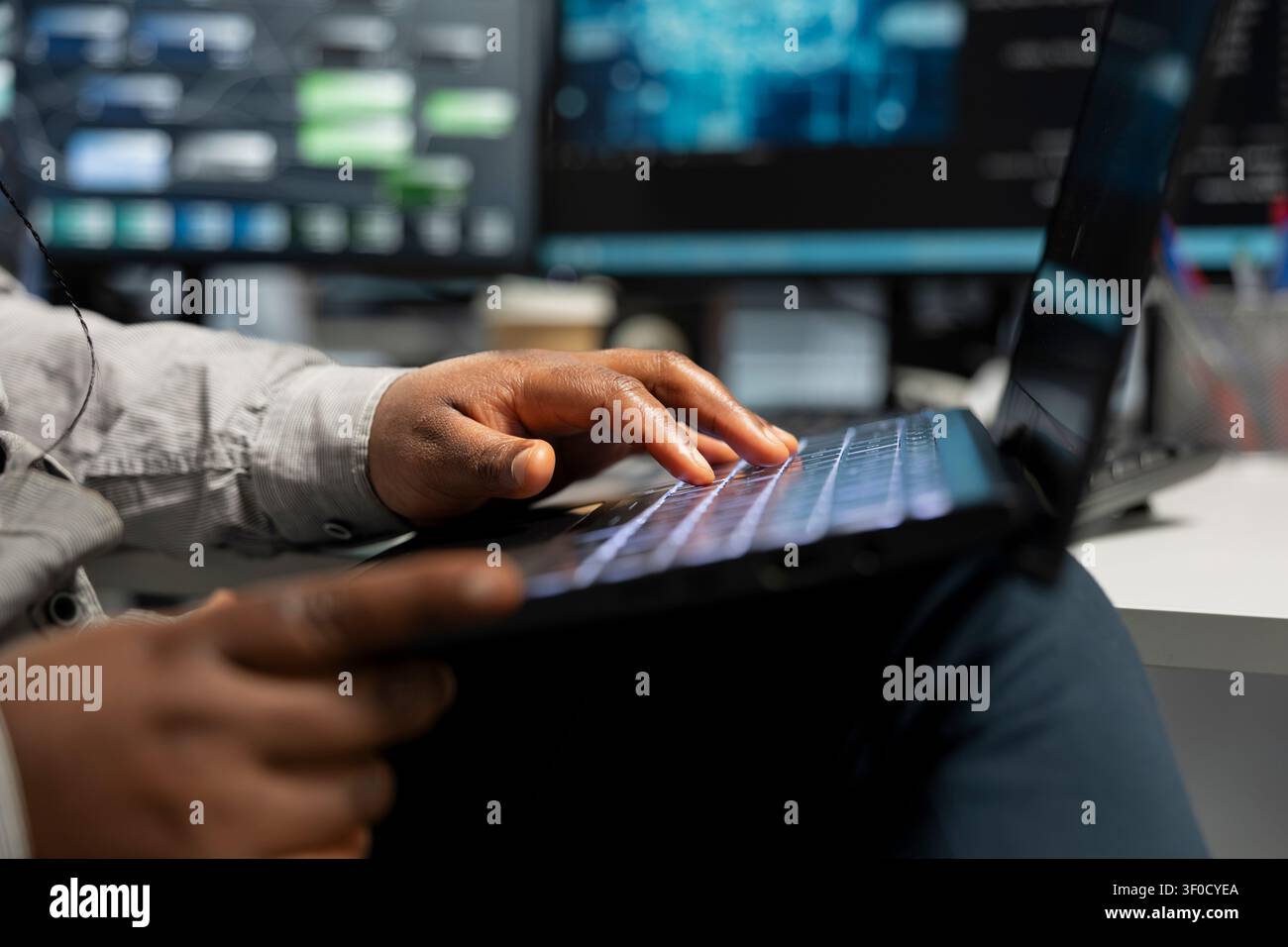 Data center technician uses a laptop to manage machine learning workloads, working with AI technology and high performance systems. Stock Photo