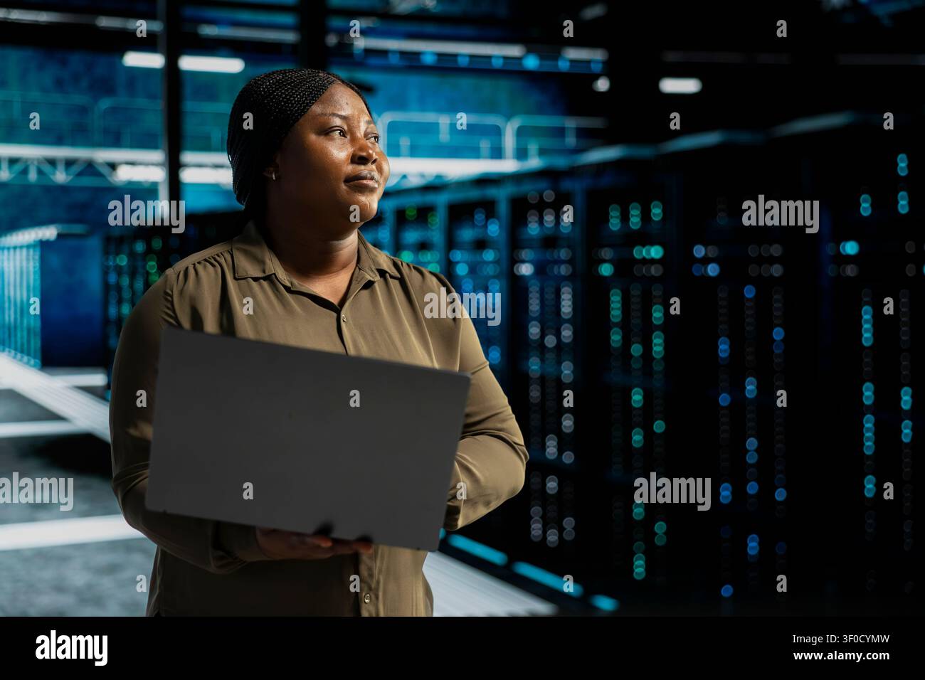 Admin working with notebook computer to do maintenance on server facility electronics processing large datasets. Stock Photo