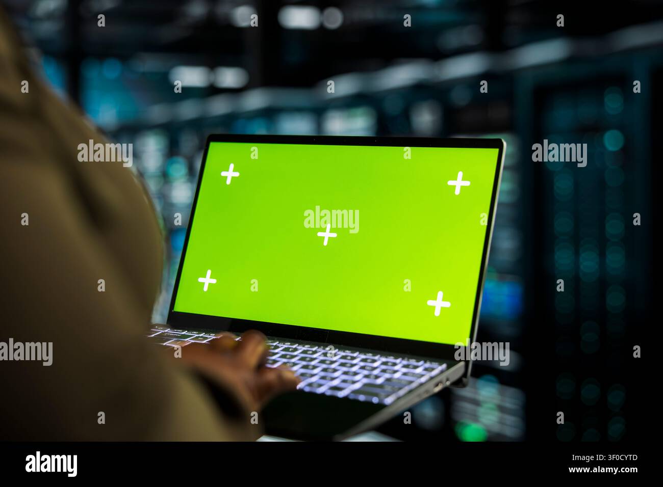 Data center programmer works with a chroma key laptop, using an editable screen to track performance metrics. Stock Photo