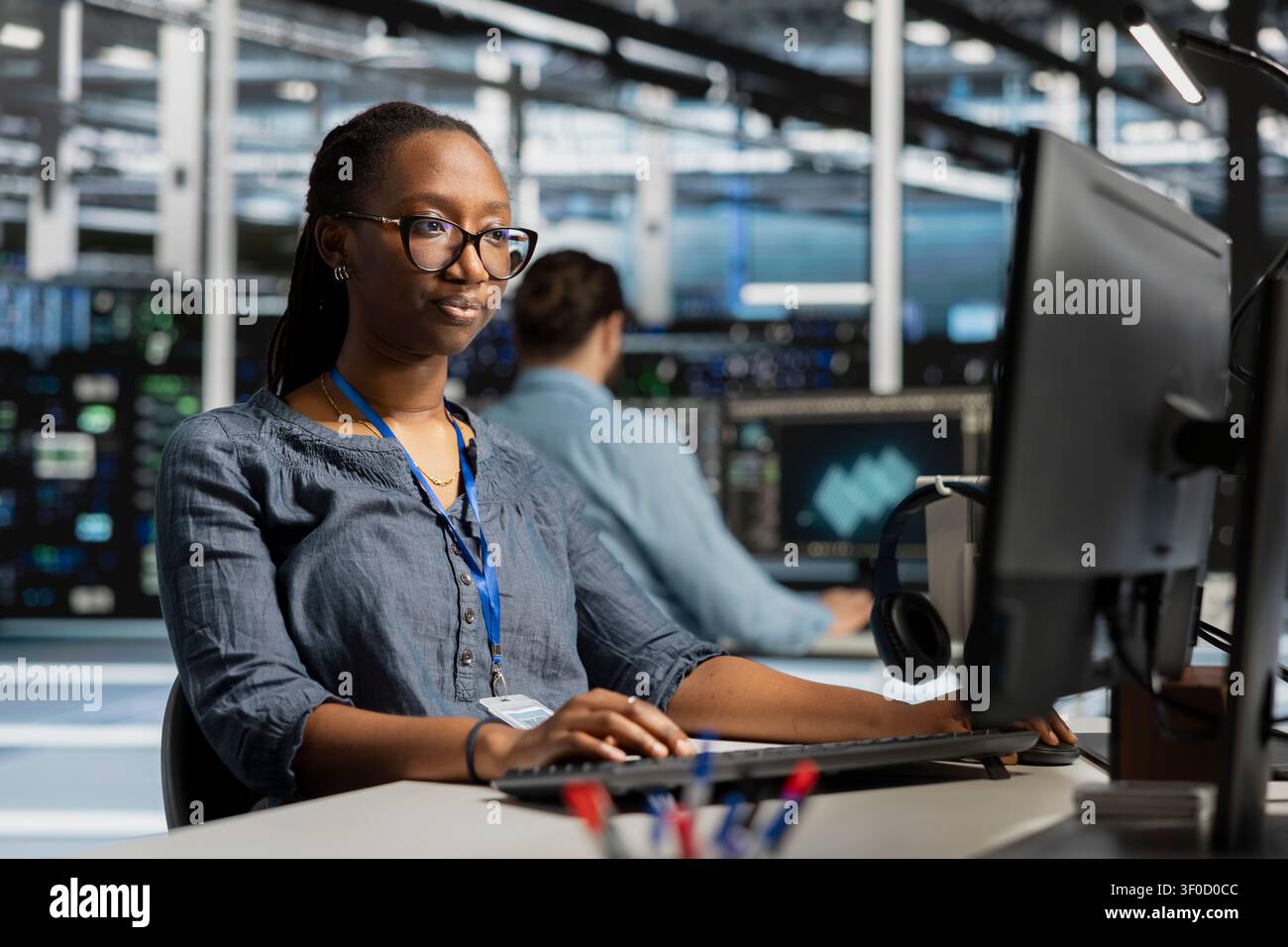 Data center programmer reviews performance analytics on a desktop computer in a data center to optimize storage systems and resource use. Stock Photo