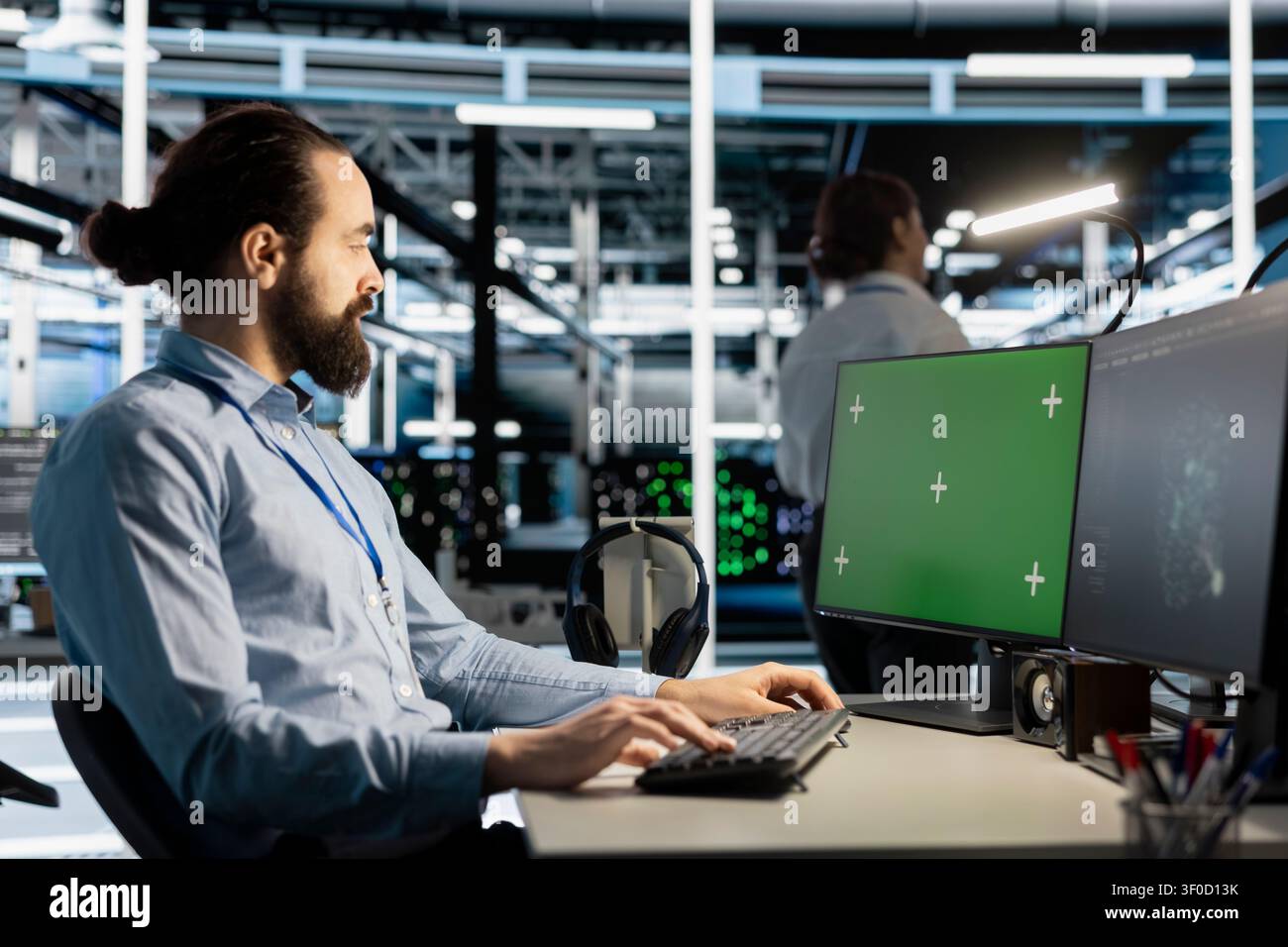 Data center engineer works with a chroma key computer, using an editable screen to update server software. Stock Photo