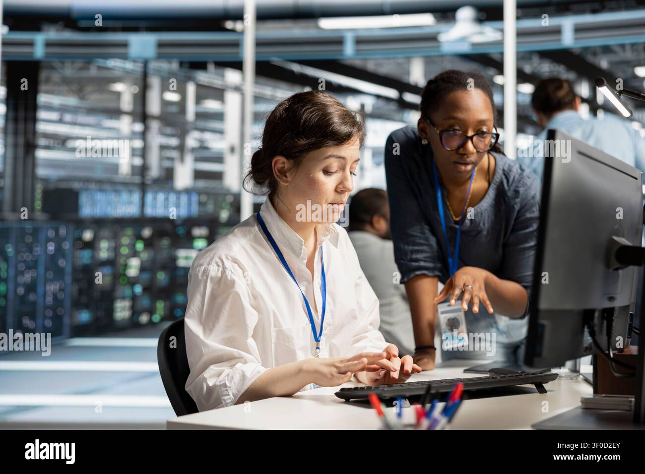 Data center colleagues collaborate on coding and AI automation scripts while reviewing server infrastructure together. Stock Photo