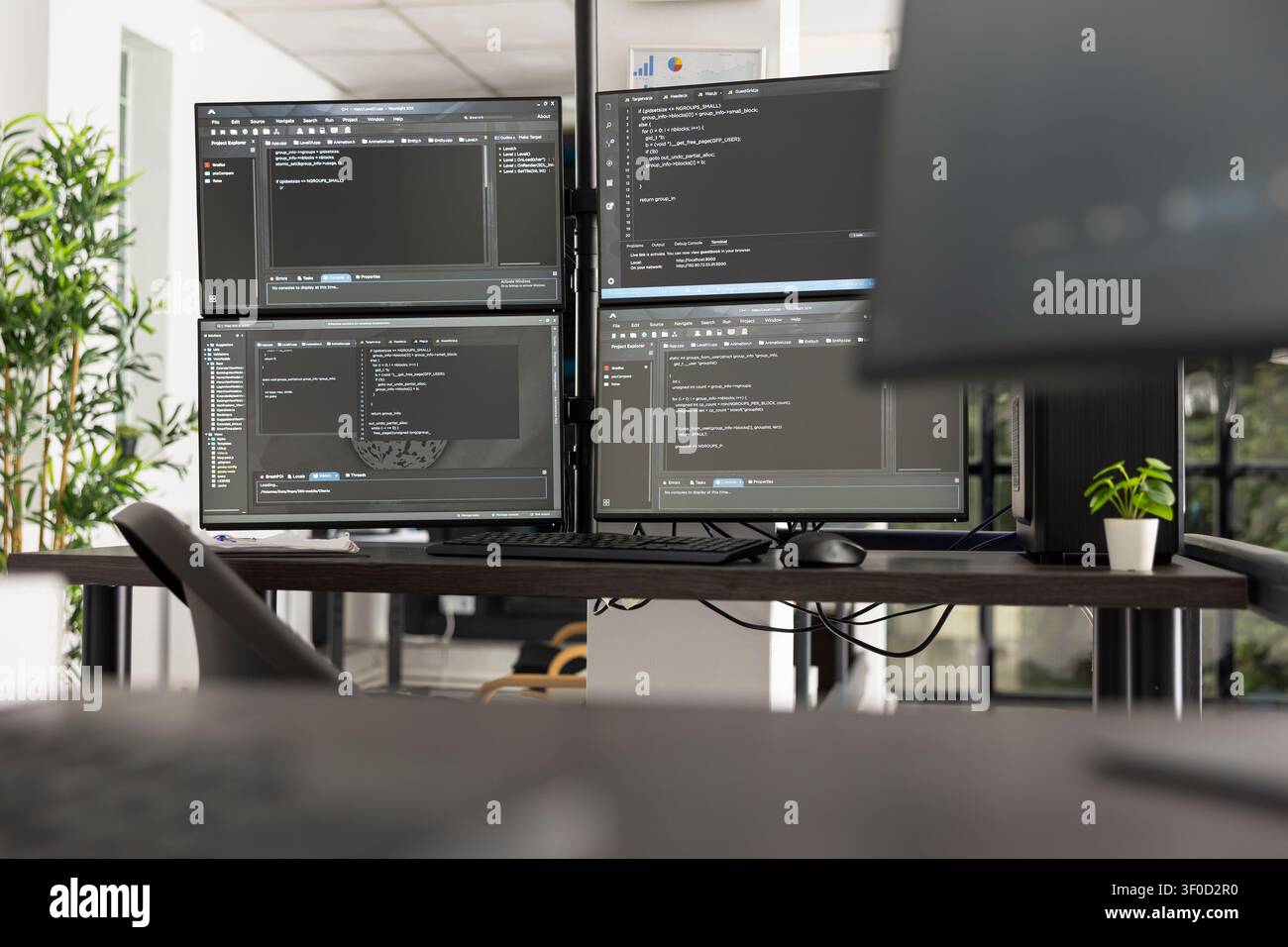 Empty IT office with several monitors displaying programming code and application data. Technology focused workspace illustrates software development, networking, and modern corporate innovation. Stock Photo