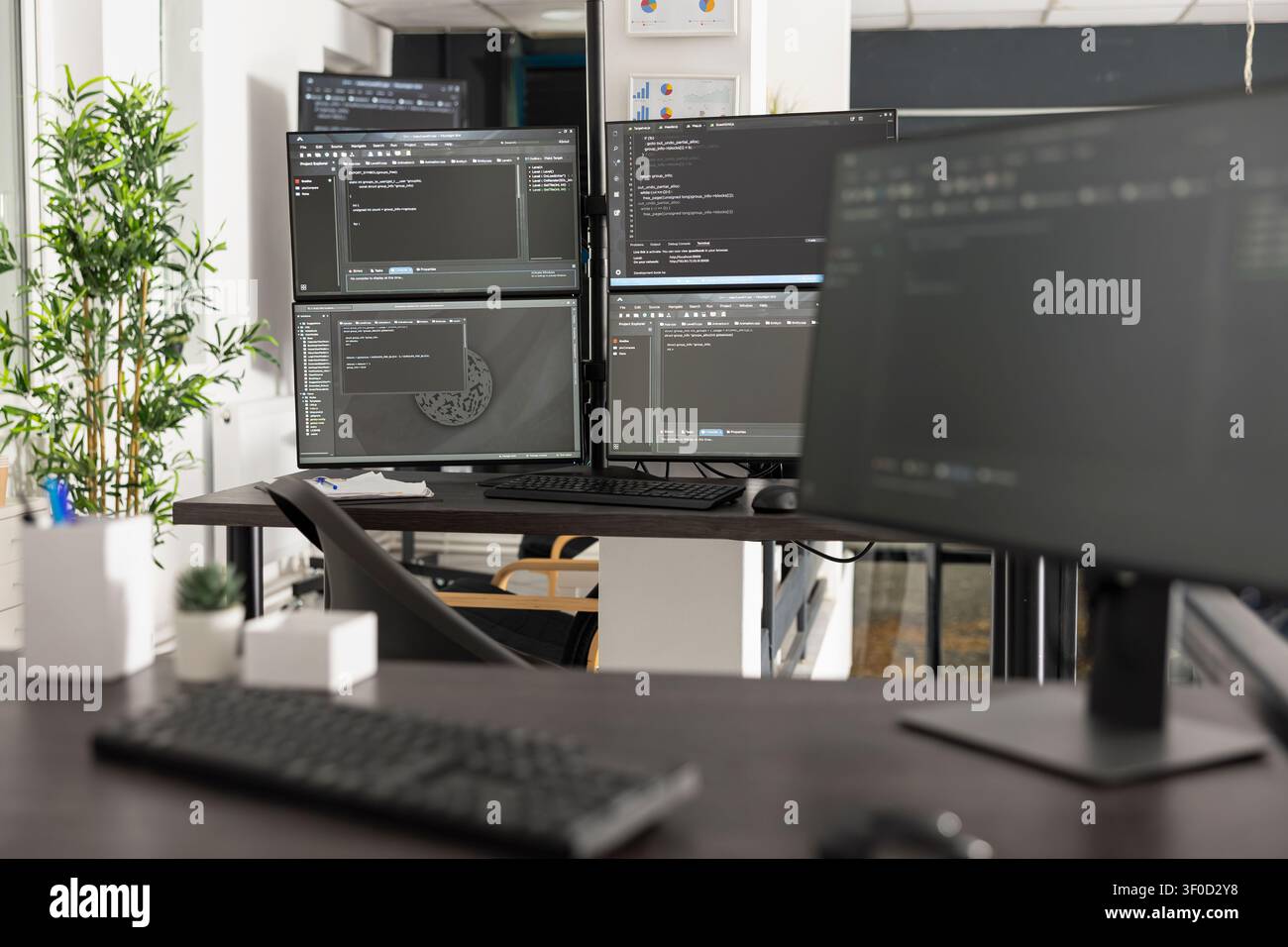 Empty office shows multiple computer screens filled with programming syntax and algorithms. Professional workspace represents web development, cybersecurity and digital business solutions. Stock Photo