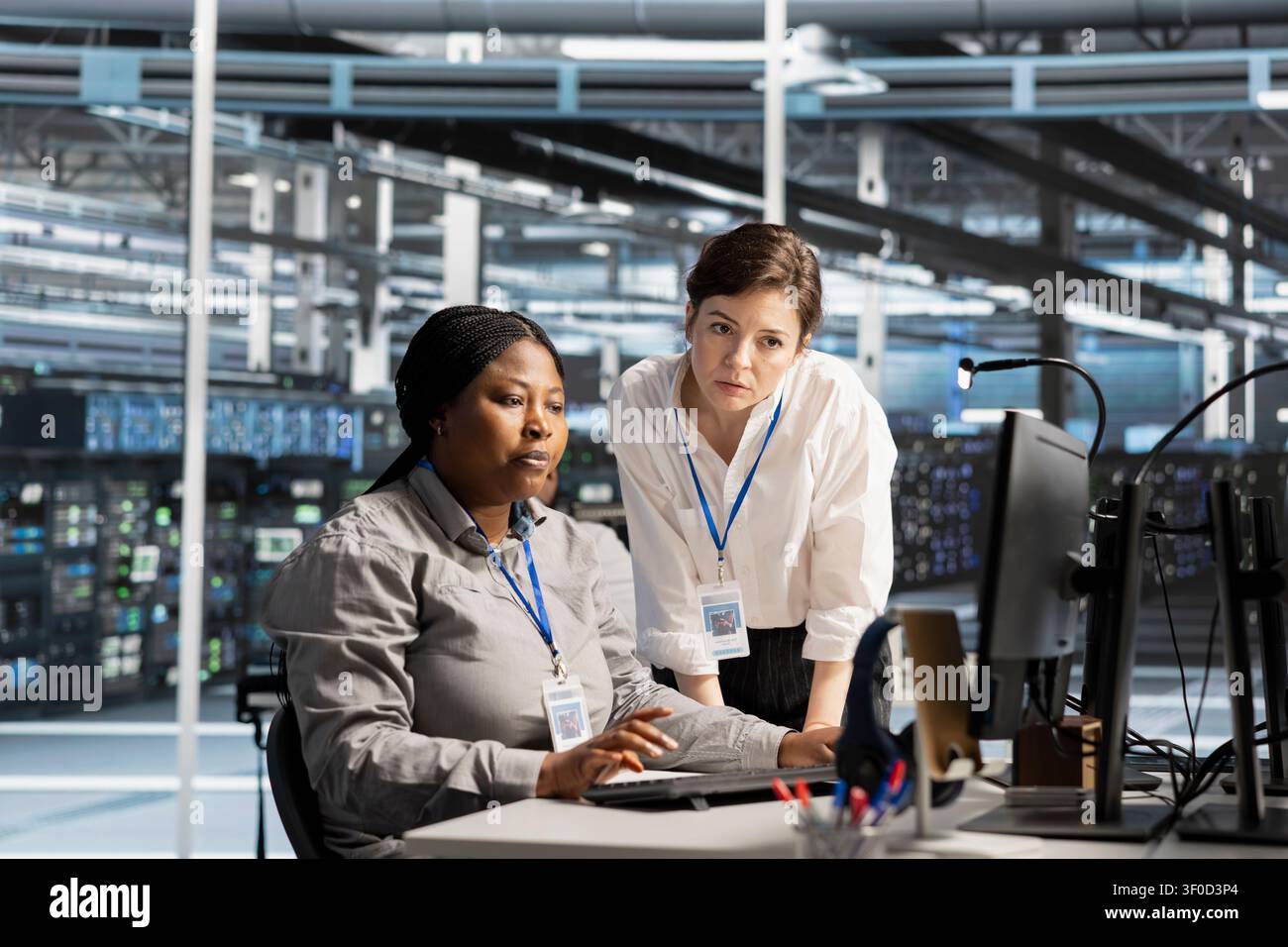 Data center colleagues collaborate on technical analysis and server infrastructure management inside a high-tech facility. Stock Photo