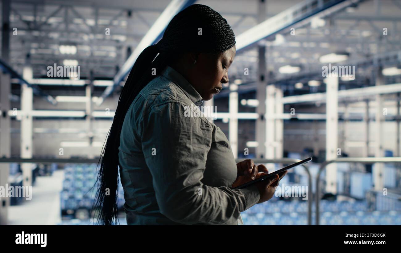 IT expert checks server environment activity working with digital tablet while walking on industrial platform. Stock Photo
