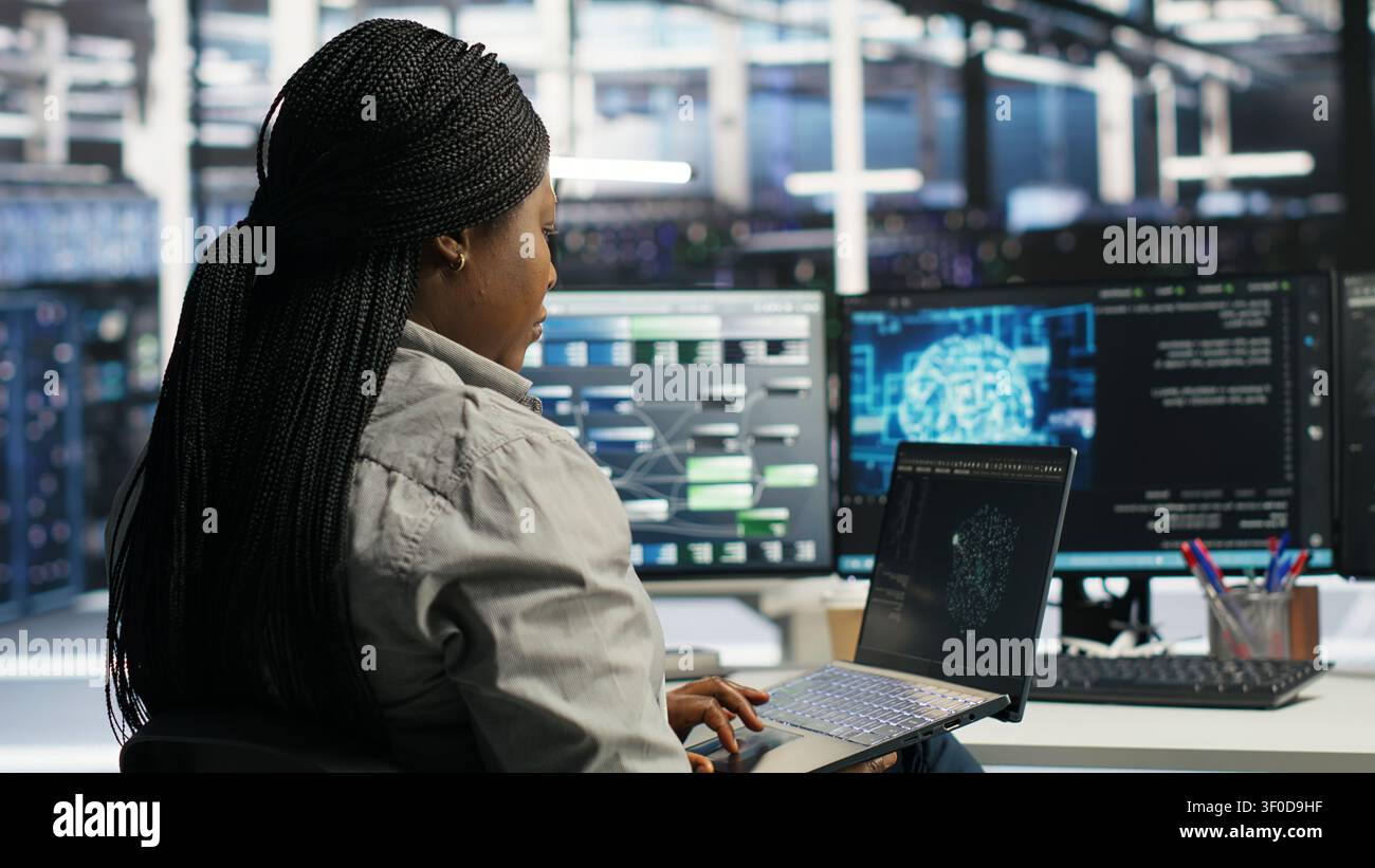 Data center IT expert working with notebook computer to apply AI technology minimizing system downtime. Stock Photo