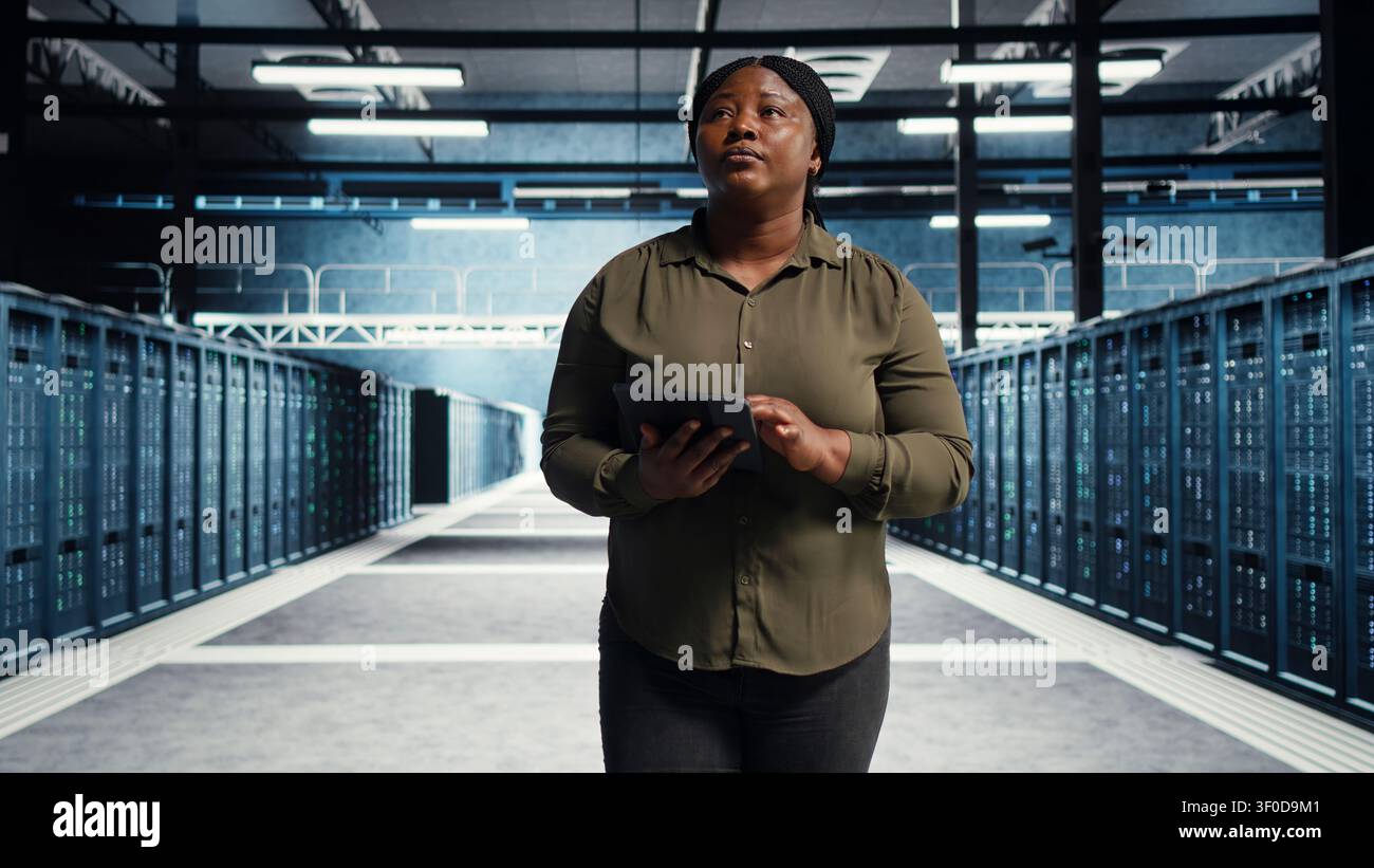 Data center engineer manages software updates in a server room to keep data center systems stable. Stock Photo