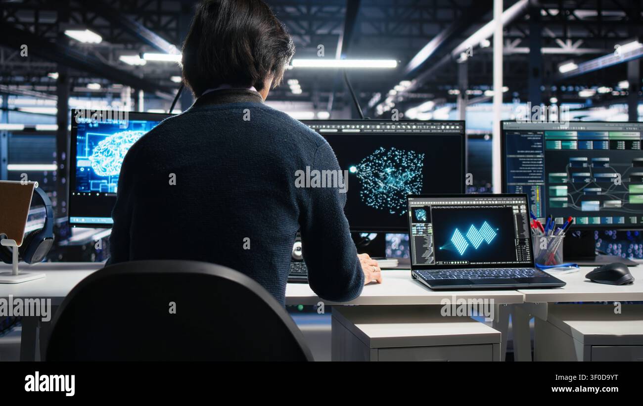 System admin entering computing facility office, checks AI diagnostics on computer, while starting work at server facility desk, enhancing AI systems configuration. Stock Photo