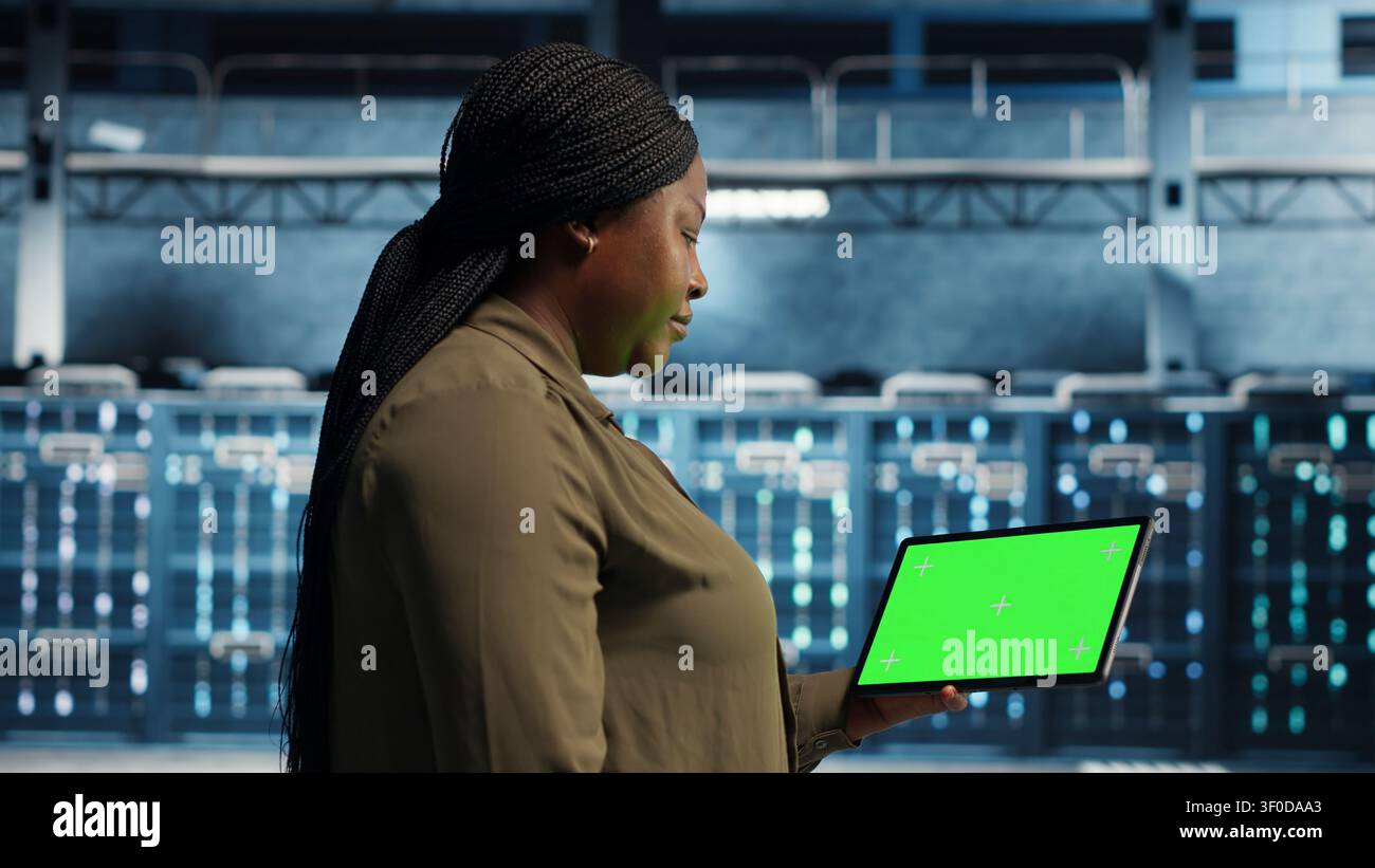 Data center administrator works with a chroma key tablet, using an editable screen to manage technical tasks. Stock Photo