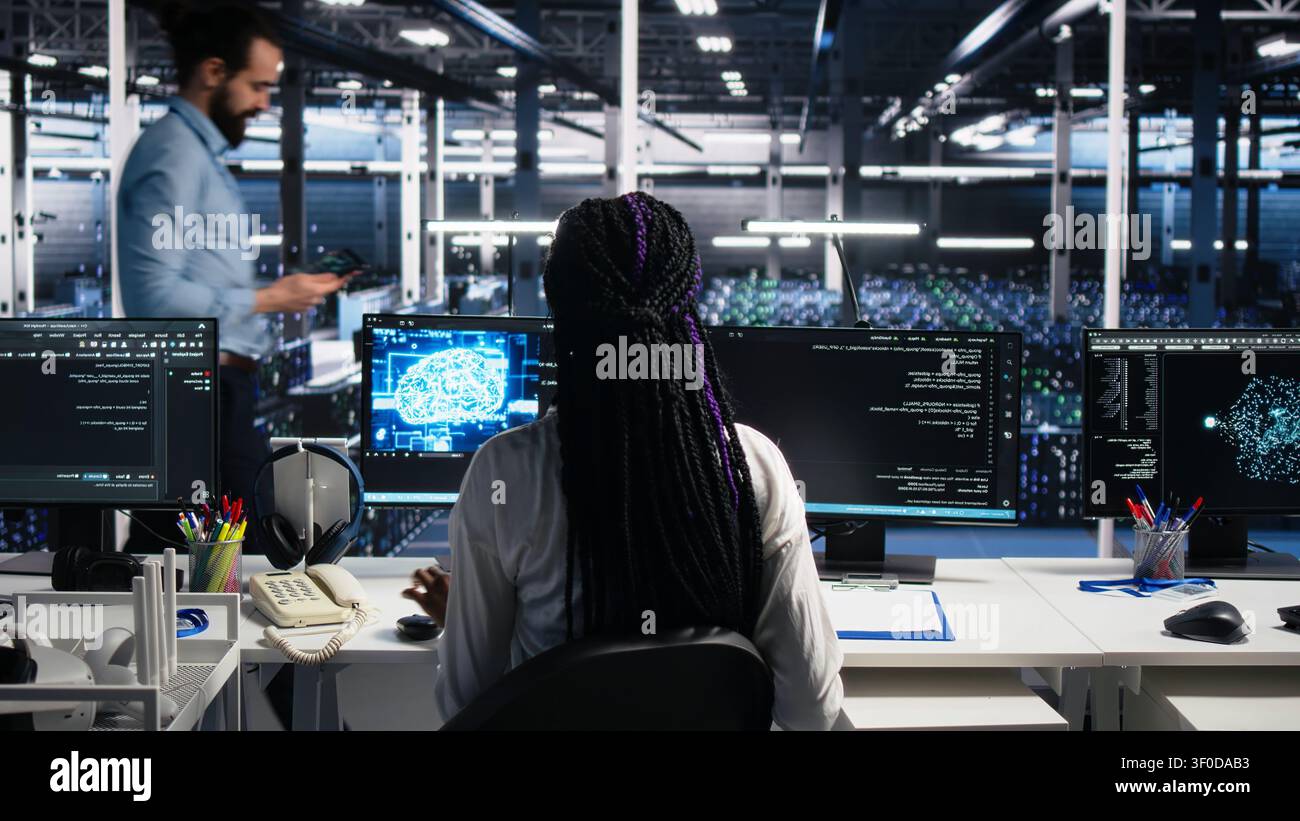 Female software programmer in computing facility checks AI diagnostics, assessing neural network operational performance, while optimizes AI systems configuration. Stock Photo