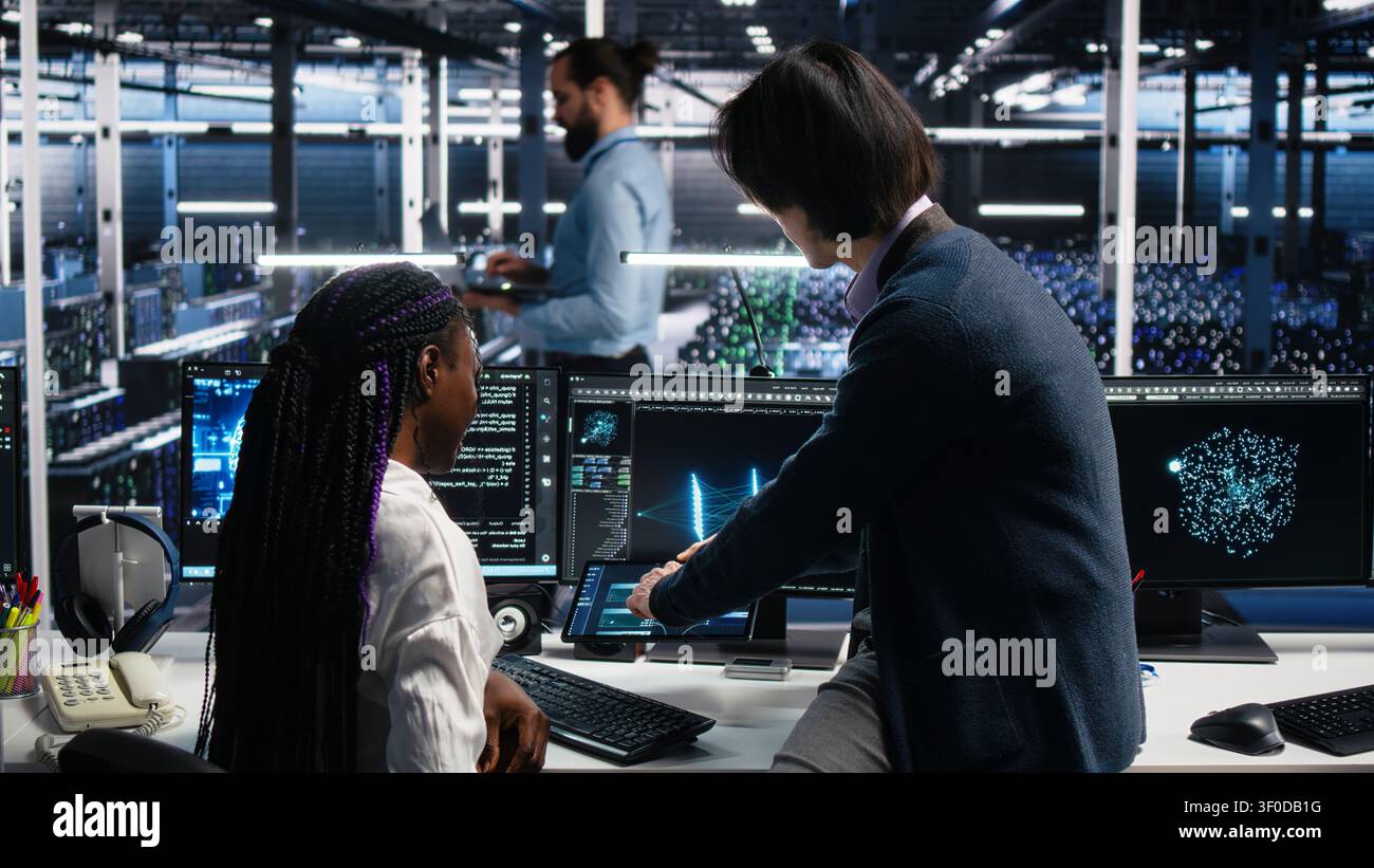 Asian man programs on a computer workstation in a data center with generative AI assistance. Stock Photo