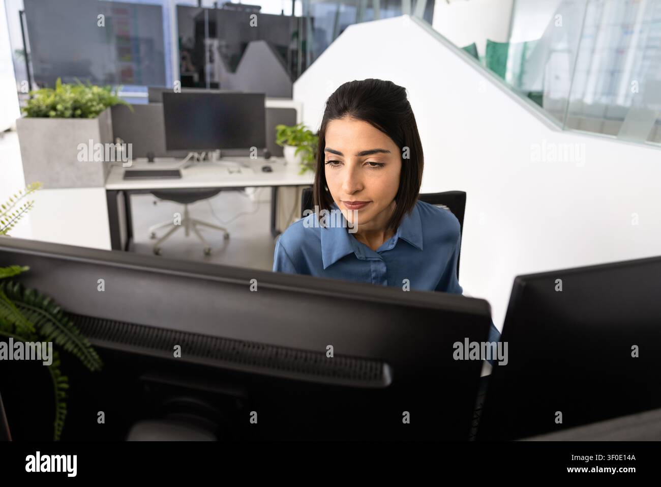 Focused office worker analyzing data on dual monitors Stock Photo