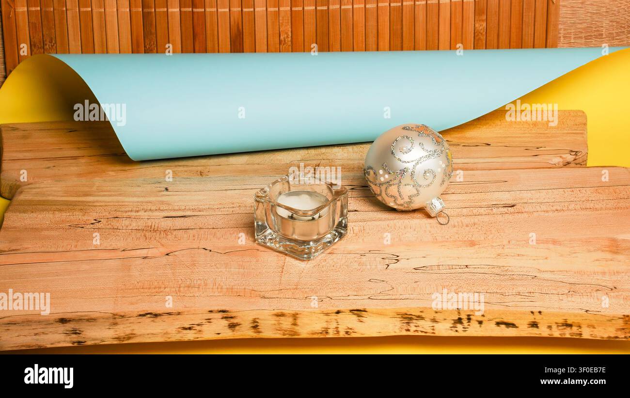 Festive holiday ornament and candle on rustic wooden surface with bamboo background Stock Photo