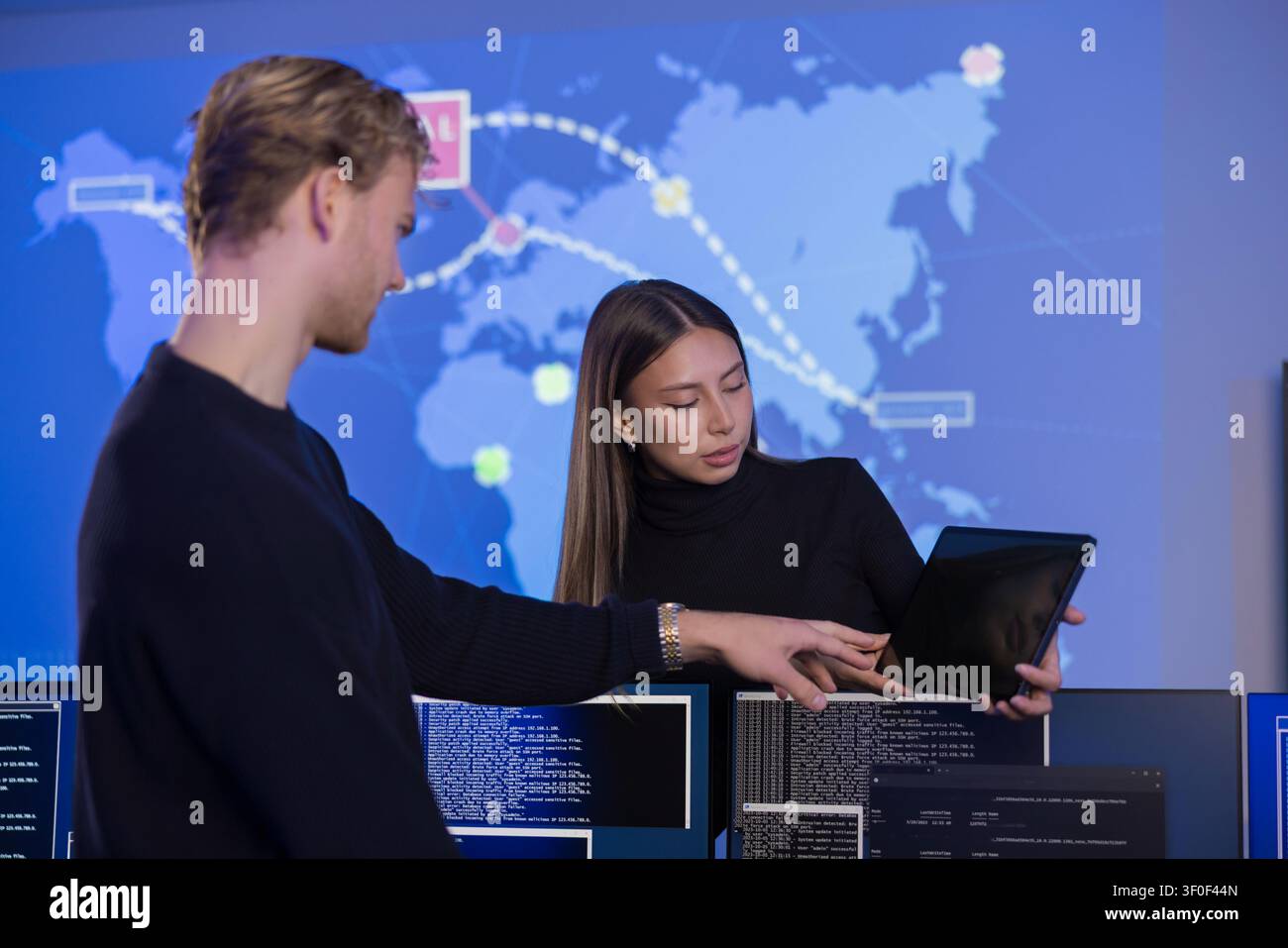 Team collaborating in a cybersecurity operations center with data visualization screens Stock Photo