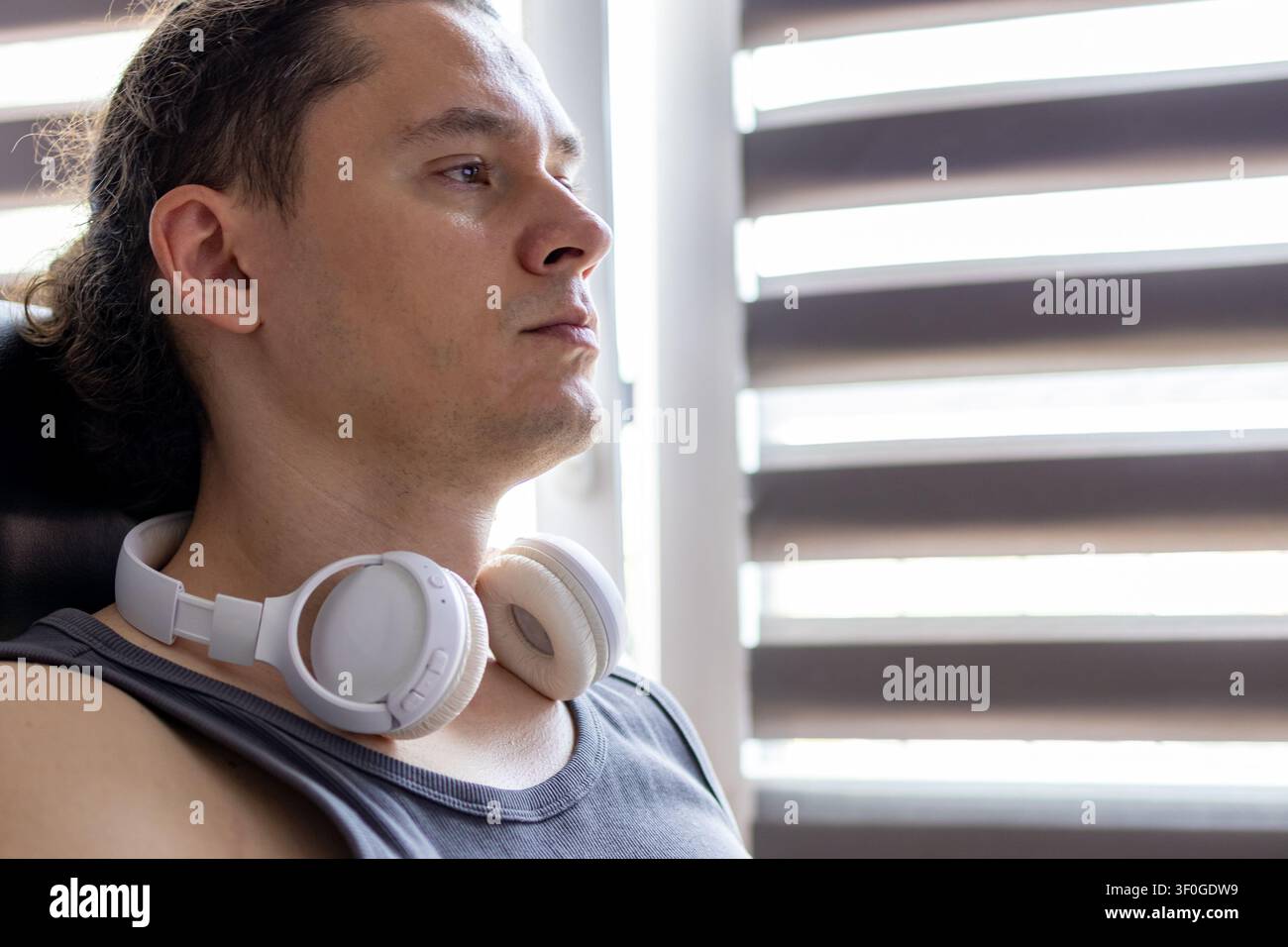 Portrait of a focused middle aged man with white wireless over-ear headphones resting around his neck while thinking during work at  home. Concept of Stock Photo