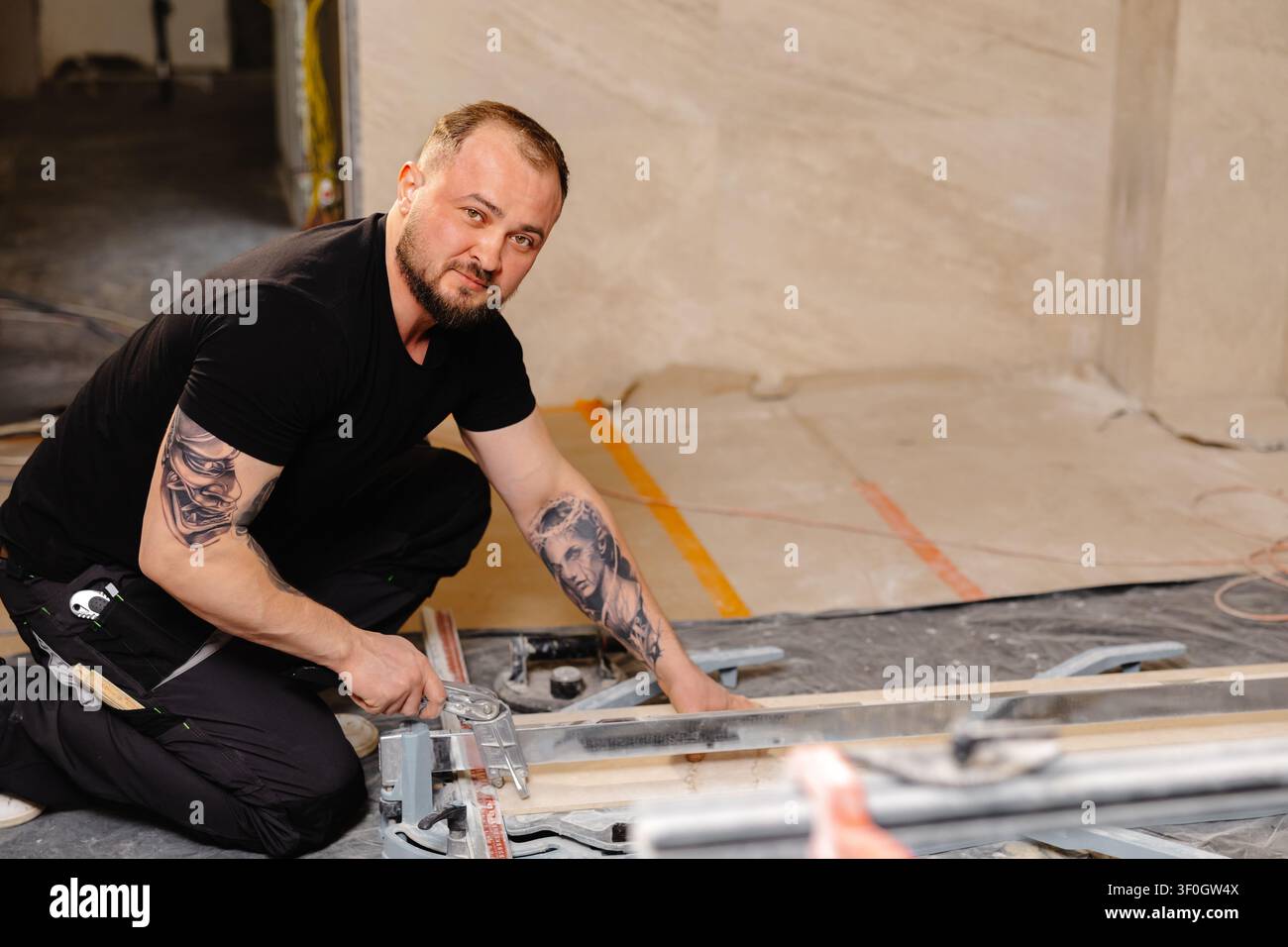 Construction worker cutting ceramic tile using tile cutter while working on bathroom renovation Stock Photo