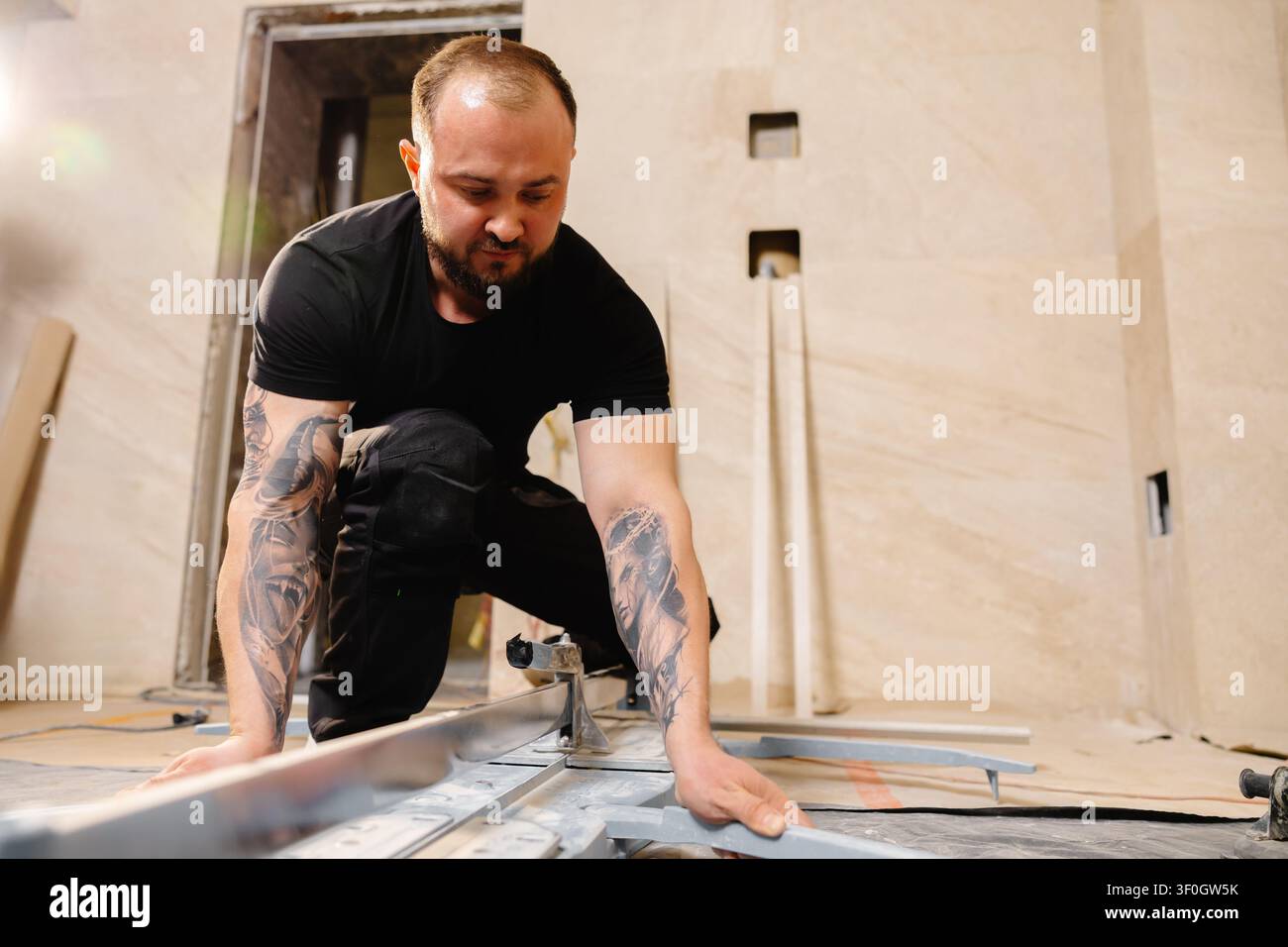 Construction worker cutting ceramic tile using manual tile cutter while working on bathroom renovation Stock Photo