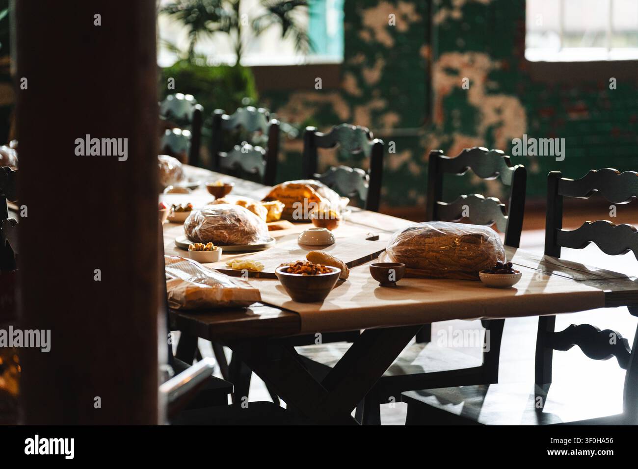 Rustic long dining table set with bread and snacks in organic cafe Stock Photo