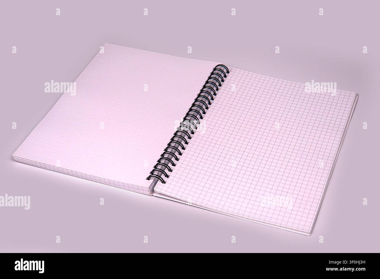 Professional spiral notebook with grid pages, centered composition, black binding, soft lighting, light gray backdrop, clean edges, smooth paper textu Stock Photo
