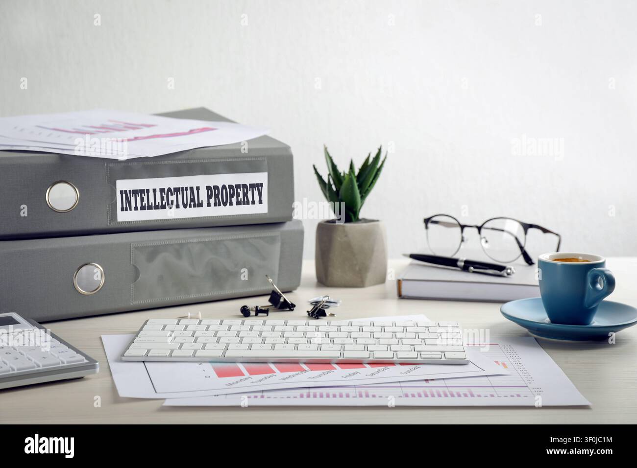 Intellectual property. Folders, computer keyboard and notebook on wooden table Stock Photo