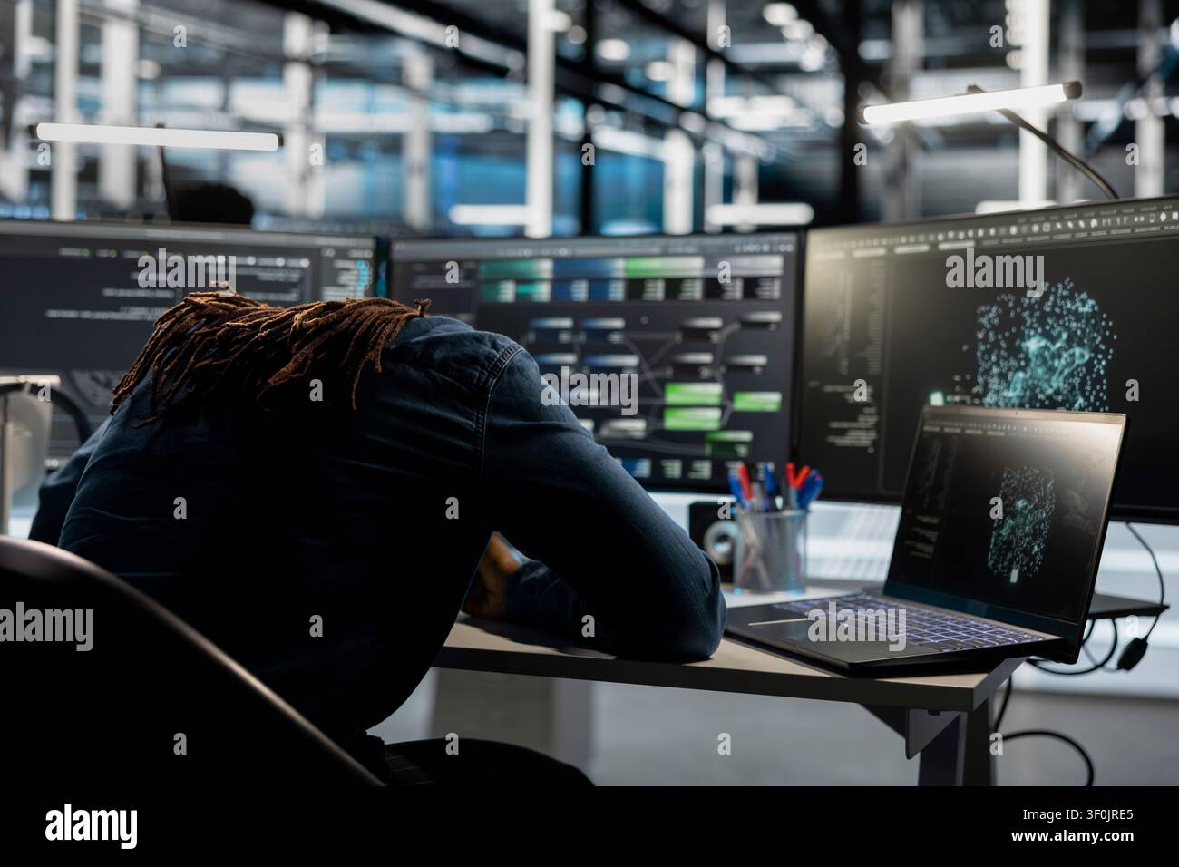 Exhausted data center engineer falls asleep while reviewing data analysis graph to reduce equipment failure. Stock Photo