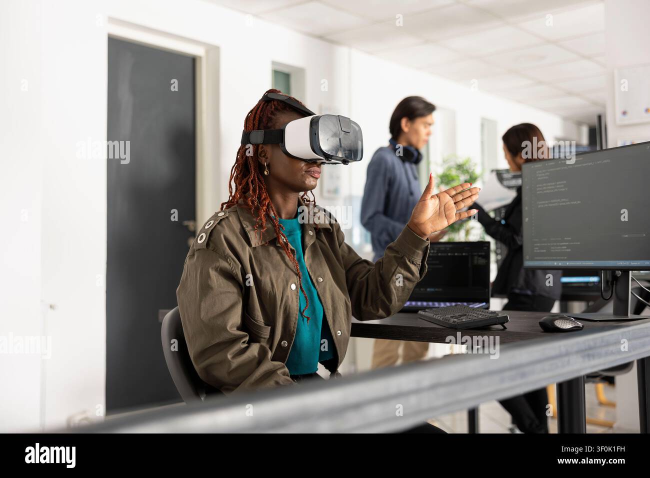 Black female developer with VR glasses, interacting with 3D coding interface. Woman analyzes explores virtual technology, demonstrating innovative software development at startup tech company. Stock Photo