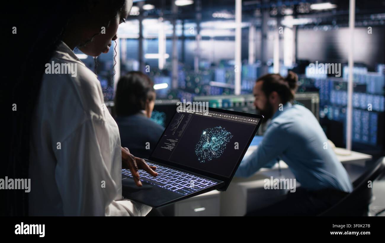 Data center technician reviews AI systems and neural network parameters on a tablet inside a data center. Stock Photo