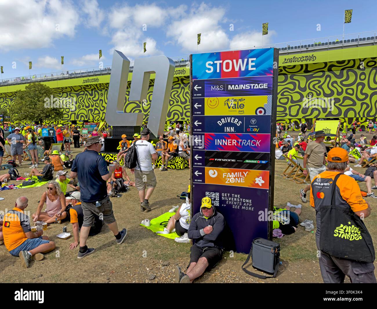 LN Crowds relax beneath the brightly decorated Landostand grandstand near Stowe Corner during Silverstone’s 2026 British Grand Prix Stock Photo