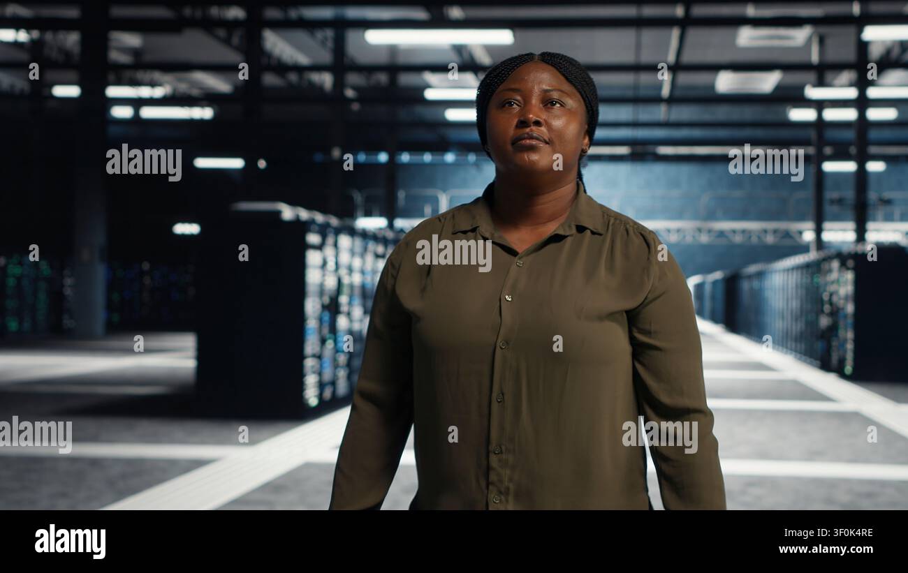Software engineer walking in server facility, checking hardware for system stability. IT administrator supervising server environment room, checking infrastructure systems. Stock Photo