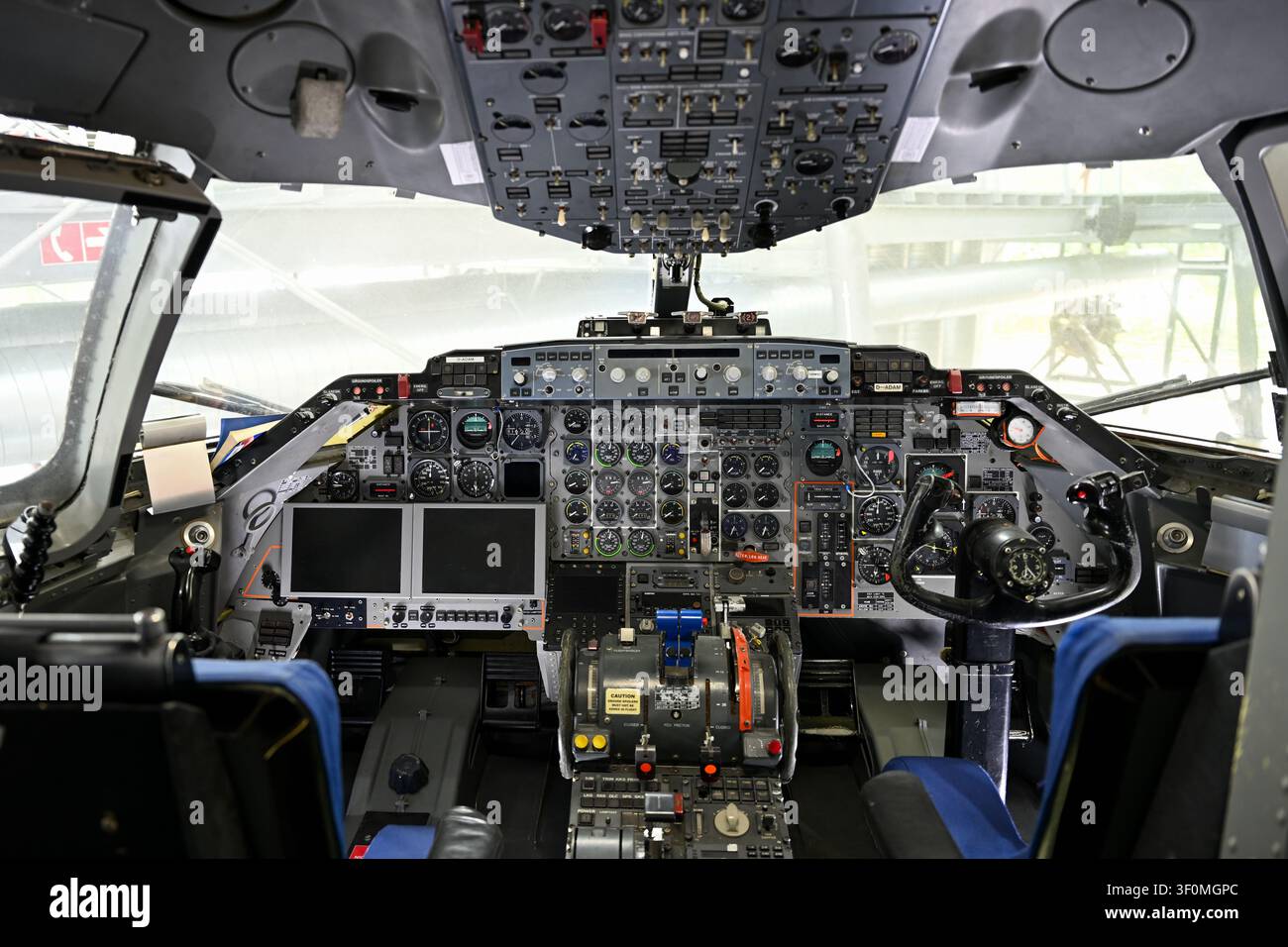 Close-up interior view of an airplane cockpit flight deck showing instrument panel, gauges, throttles and overhead switches, suitable for aviation. Stock Photo