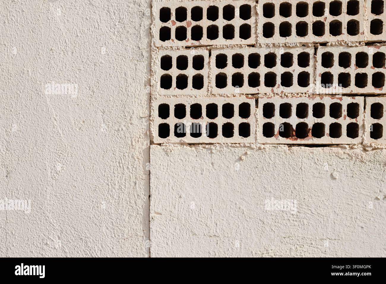 White Painted Wall with Exposed Perforated Bricks Stock Photo