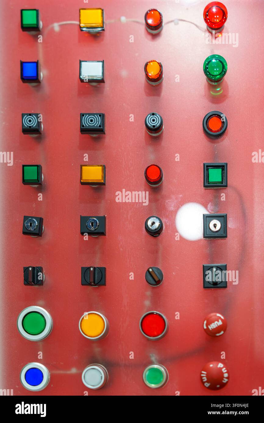 A display board featuring an array of industrial push buttons, indicator lamps, and rotary selector switches in various shapes and colors for machiner Stock Photo
