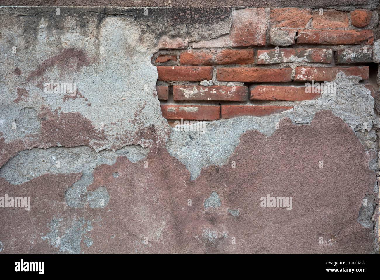 Old wall texture with cracked peeling plaster and exposed red bricks Stock Photo