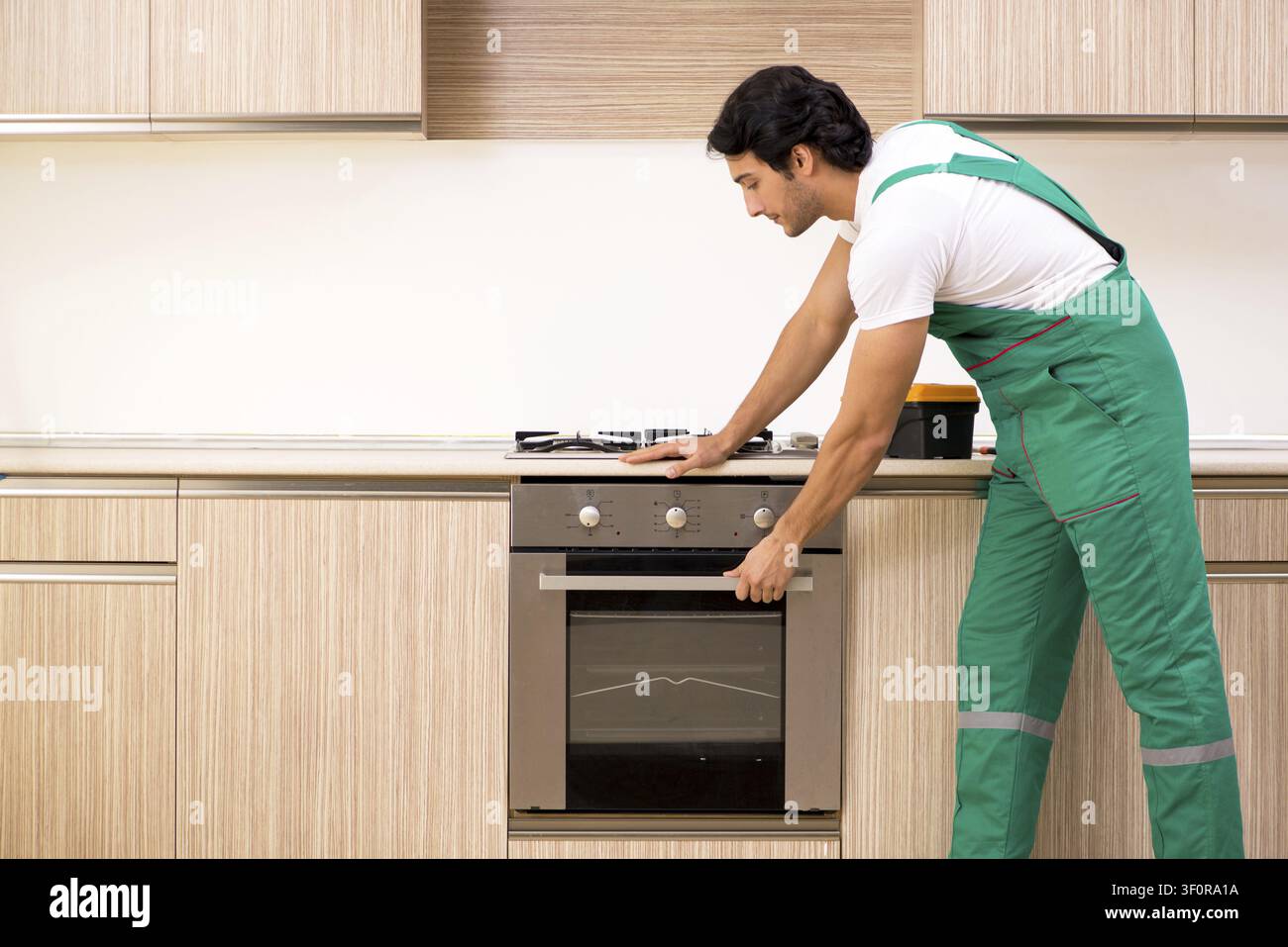 Young contractor repairing oven in kitchen Stock Photo