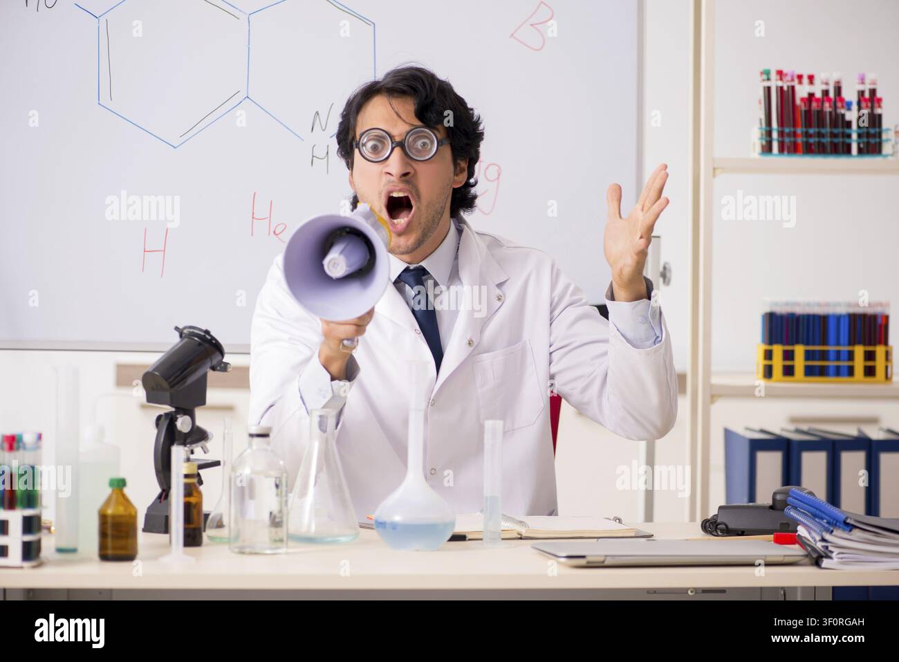 Young funny chemist in front of white board Stock Photo