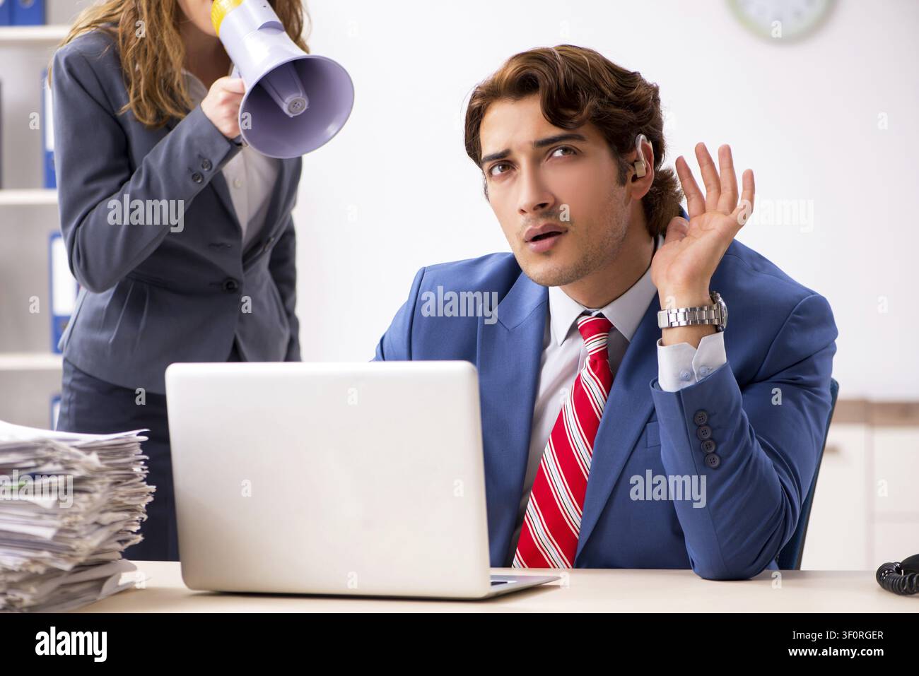 Deaf employee using hearing aid talking to boss Stock Photo