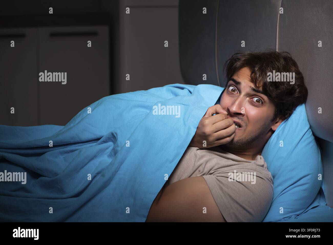 Young man scared in his bed having nightmares Stock Photo