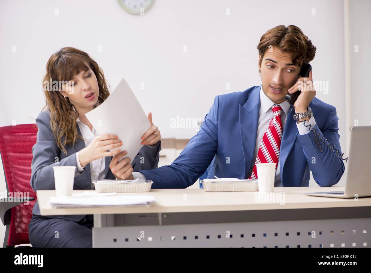 Two colleagues having lunch break at workplace Stock Photo