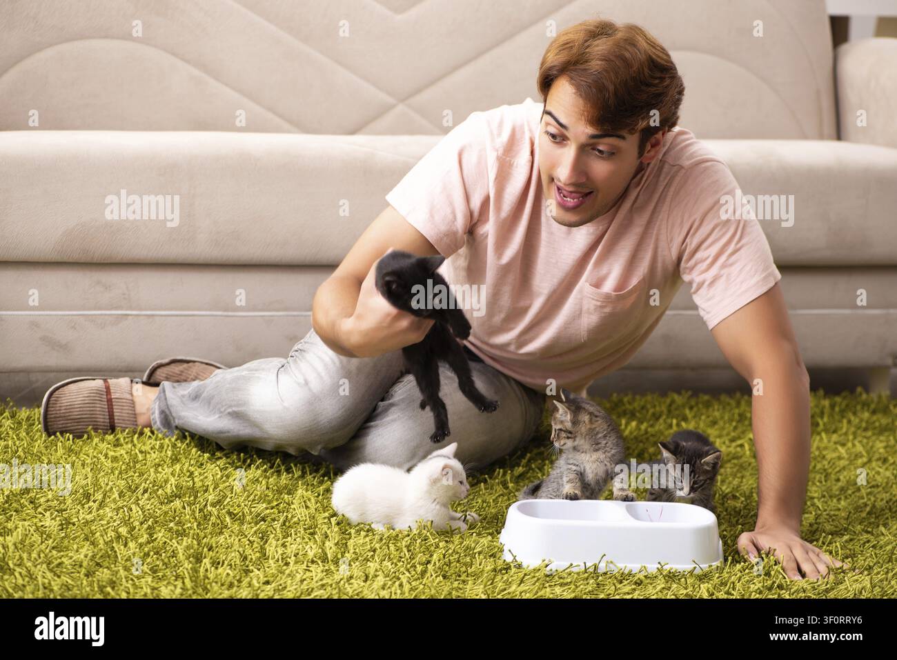 Young man playing with kitten at home Stock Photo