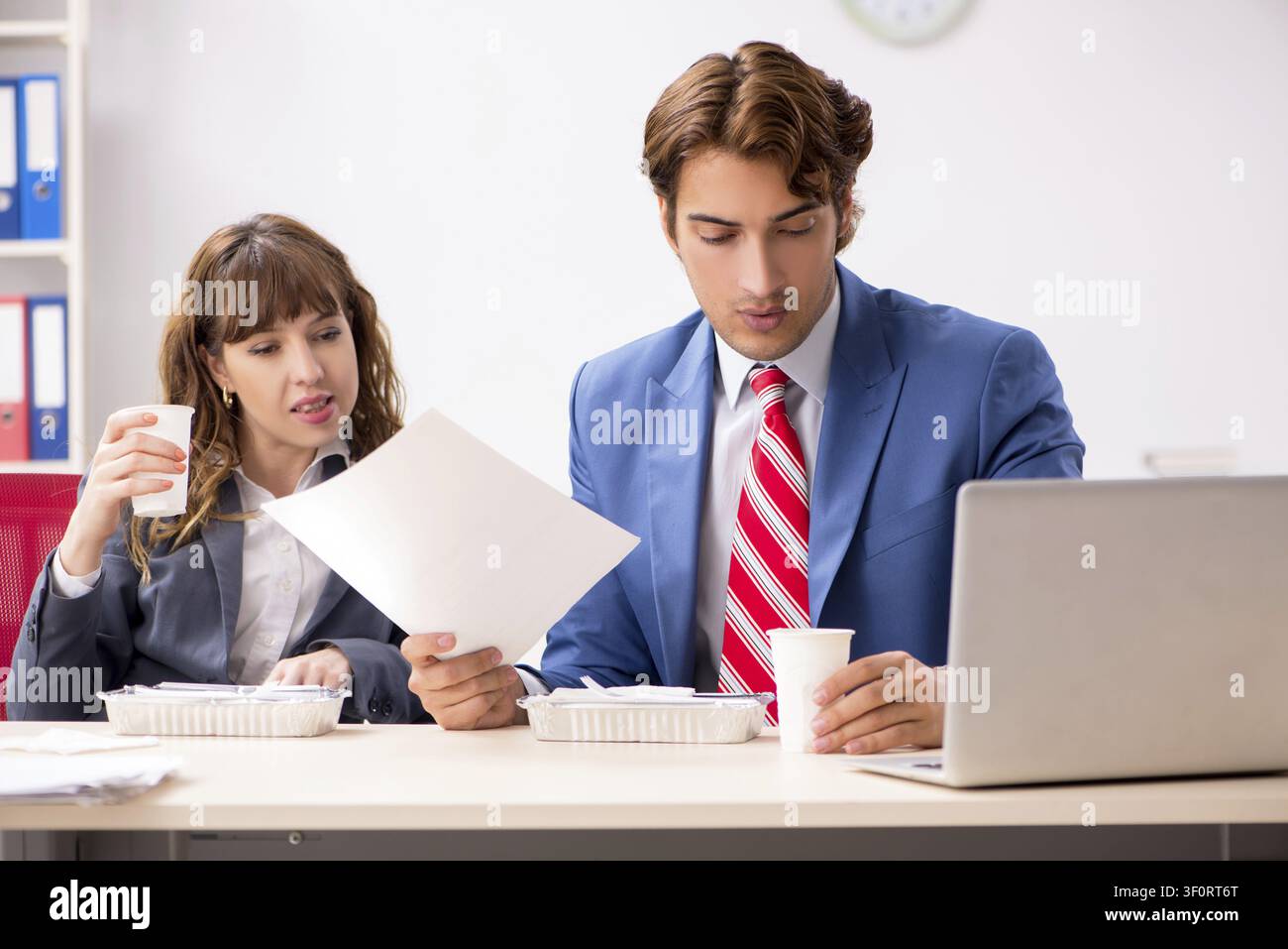 Two colleagues having lunch break at workplace Stock Photo