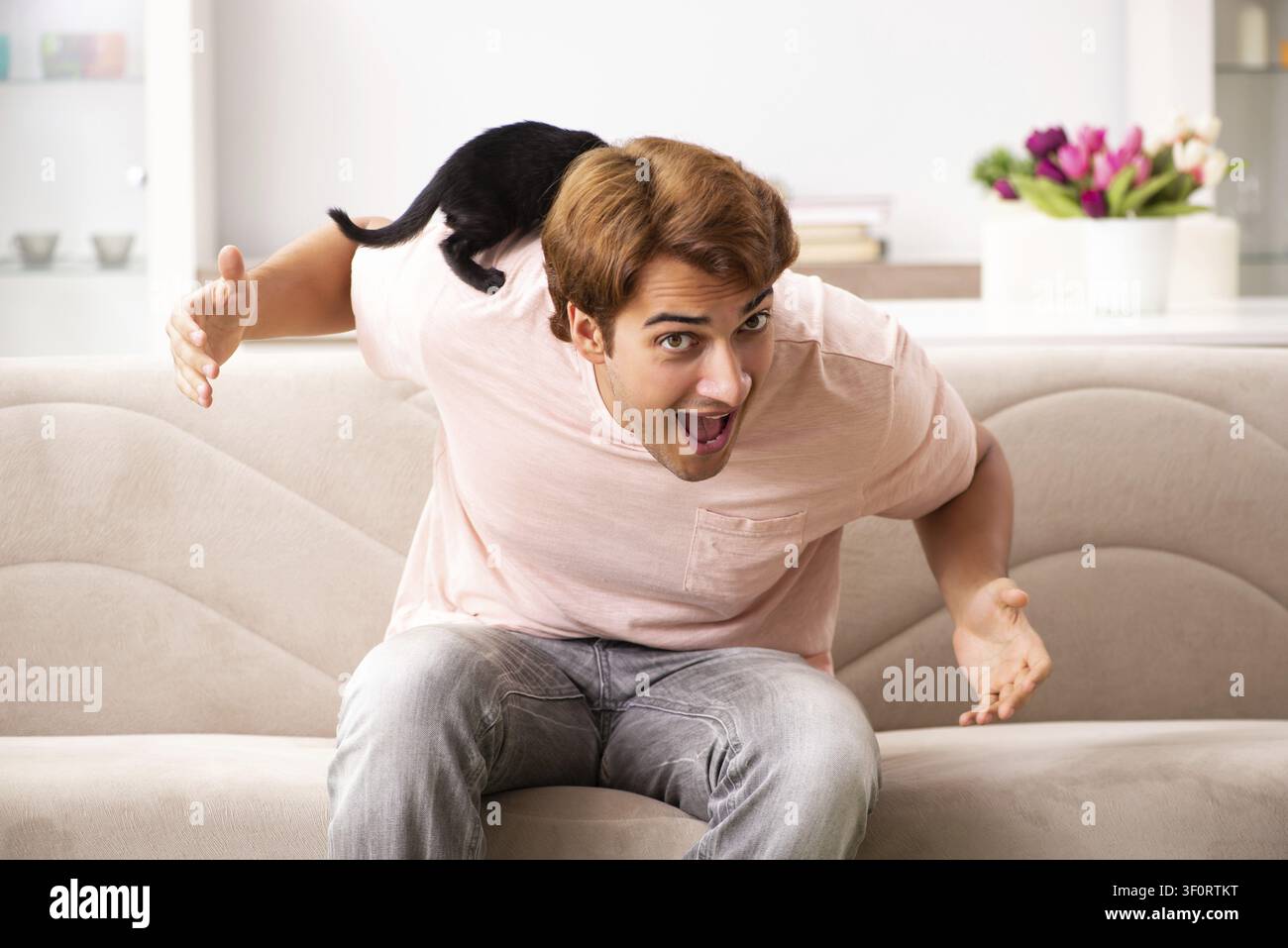 Young man playing with kitten at home Stock Photo