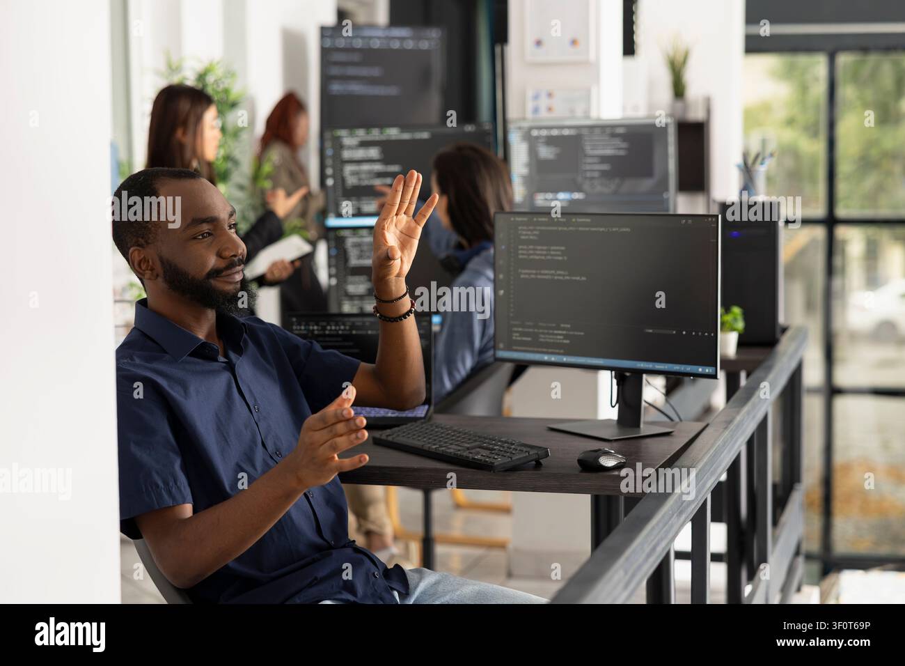 Male programmer interacts with invisible holographic interface in office. Developer explores augmented reality and advanced human computer interaction while working on innovative technology solutions. Stock Photo