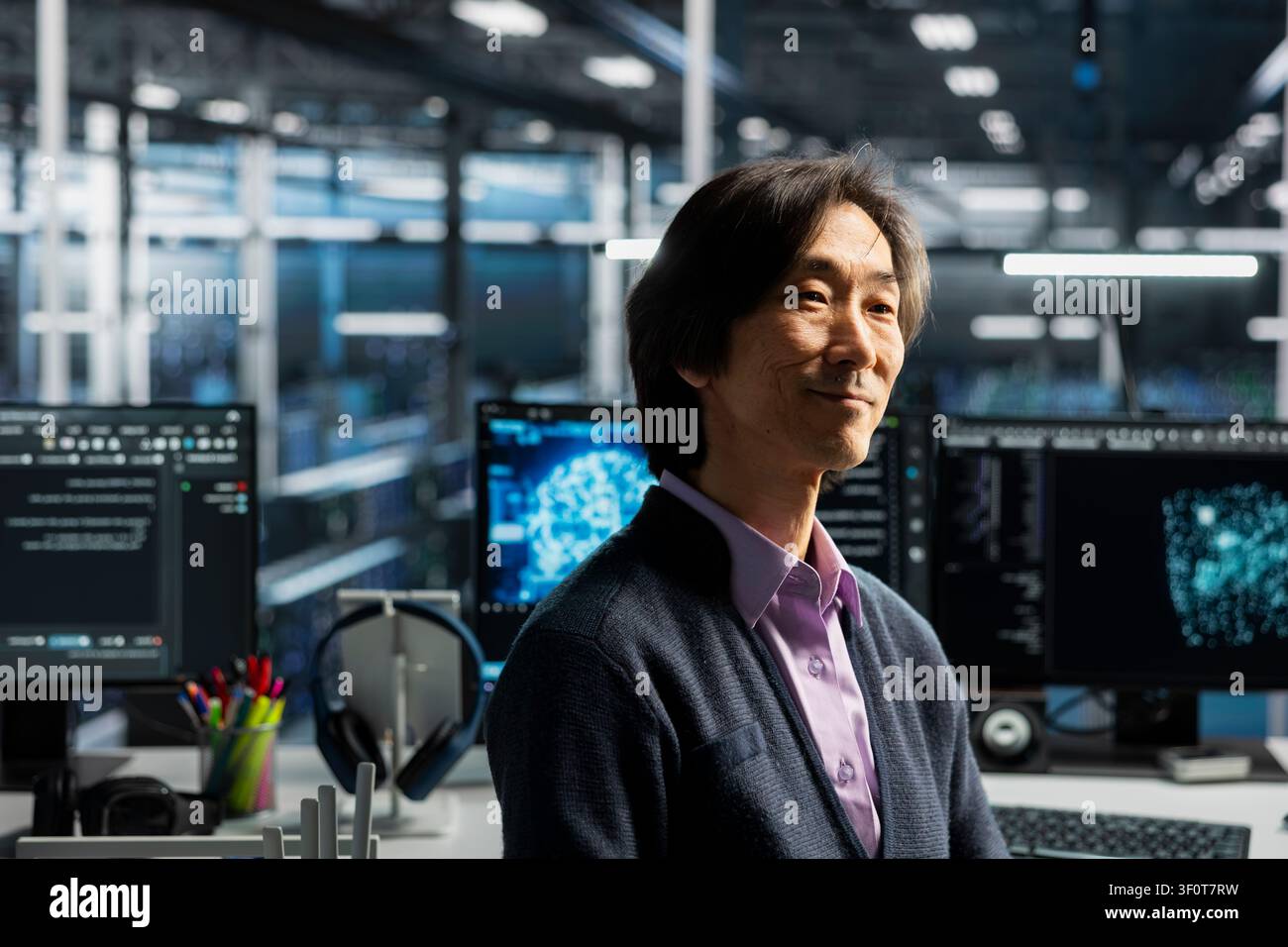 Smiling senior programmer in server room working on databases supporting AI applications. Stock Photo