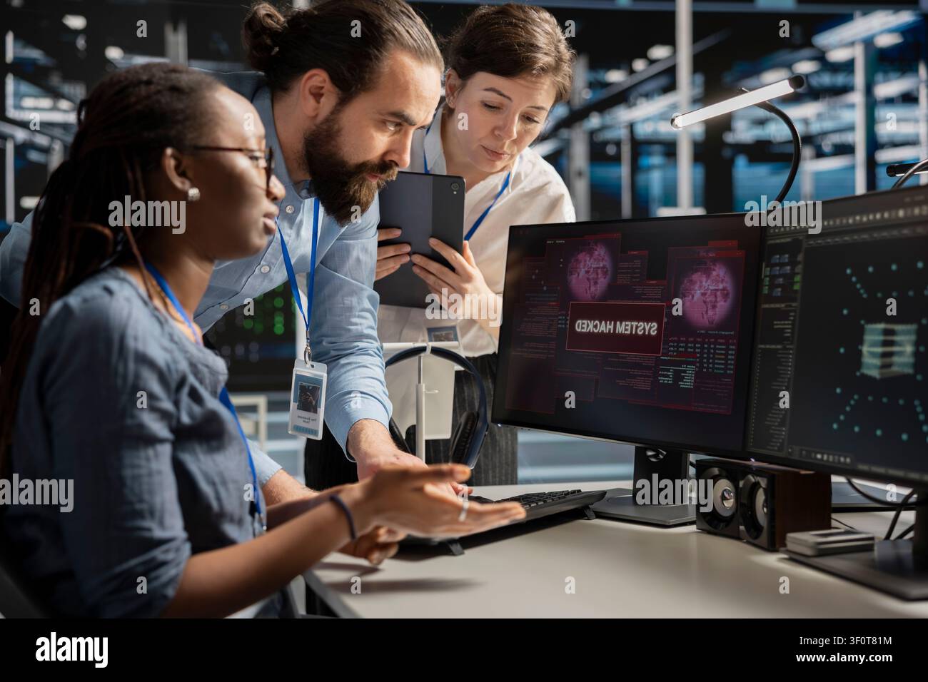 Engineering team reviews a security breach alert for a zero-day vulnerability inside a high-tech server room. Stock Photo